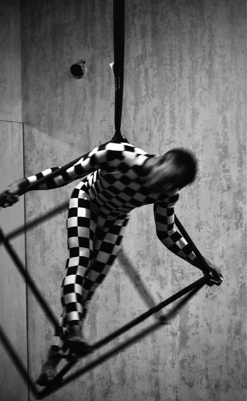 Black and White image of person within cube hanging from ceiling