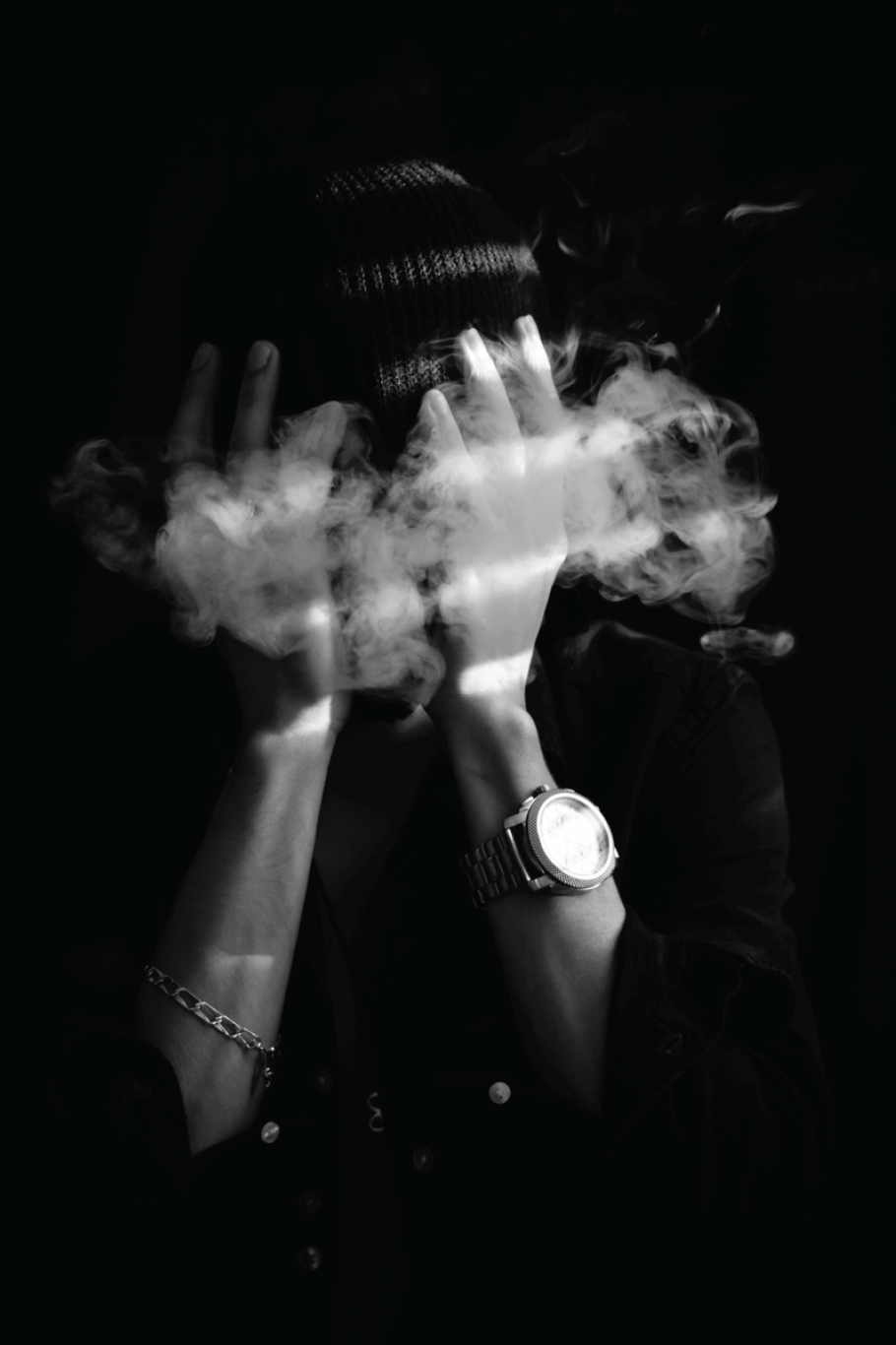 Black and White image of person with face covered as smoke engulfs them