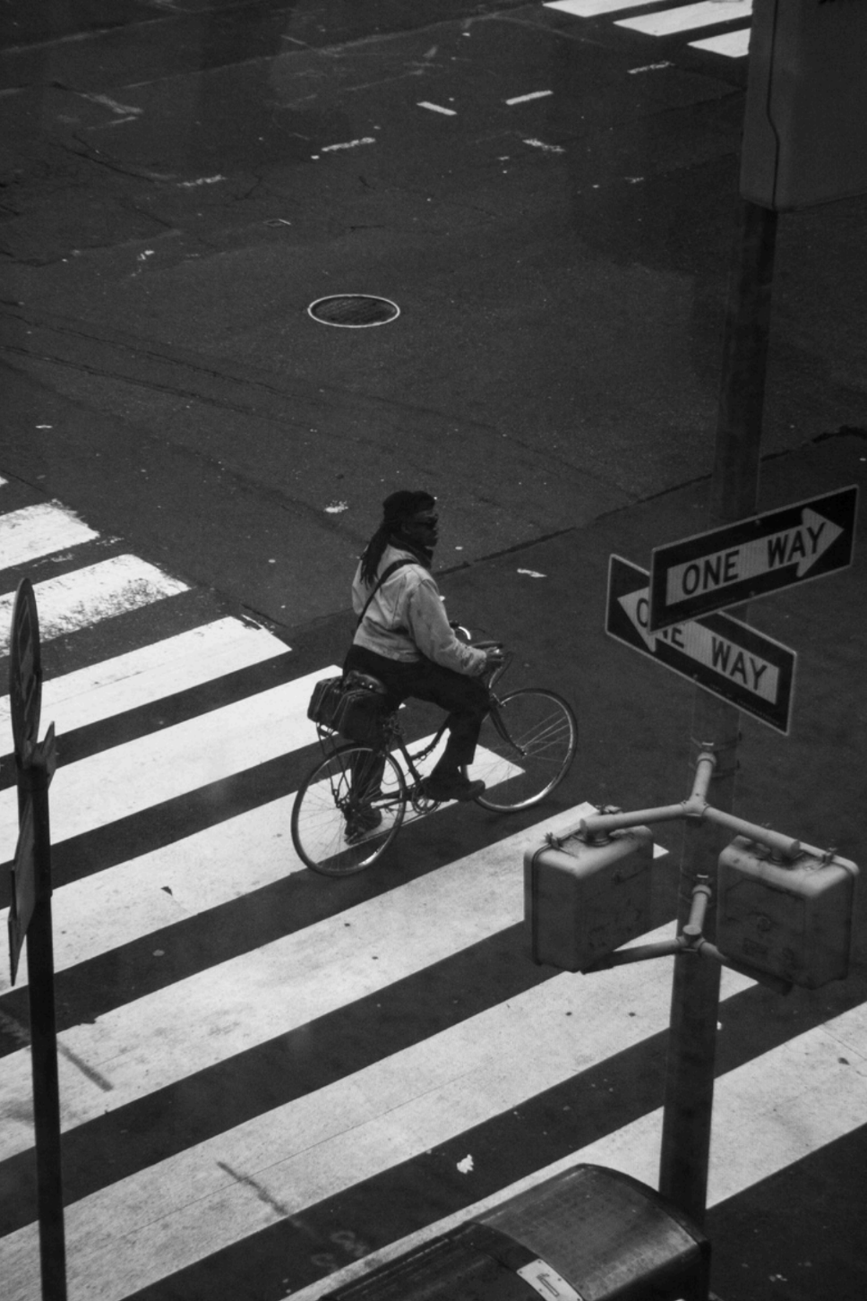 Black and White image of cyclist stopped at crossed walk