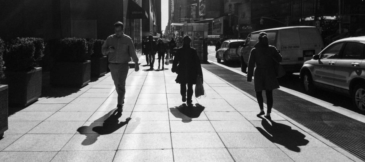 Black and White image of people walking on a wide sidewalk