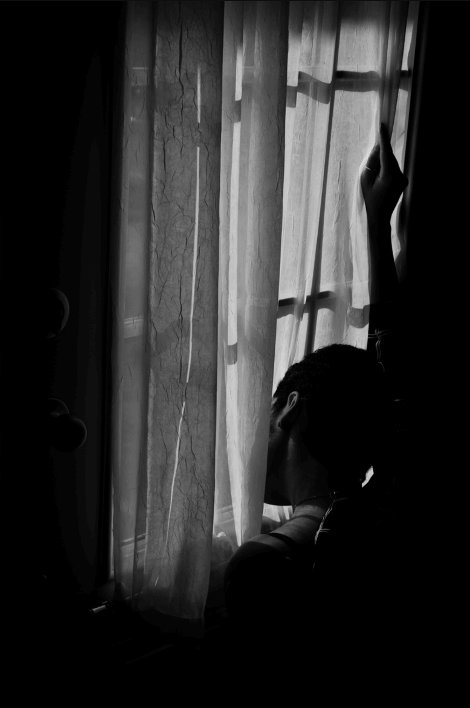 Black and White image of person looking out of window