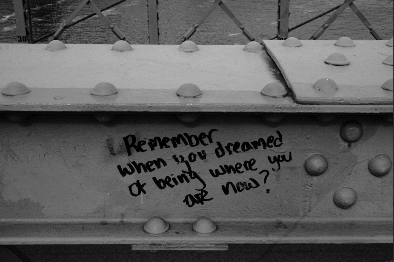 Black and White image of writing on metal beam saying "Rememberwhen you dreamed of being where you are now?"