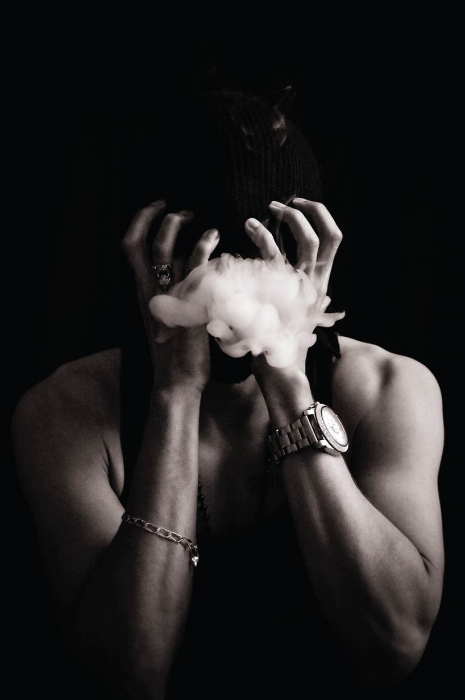 Black and White image of person with hands covering face engulfed in smoke