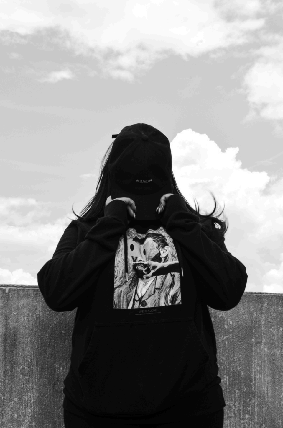Black and White artist of person in hoodie with hat covering face