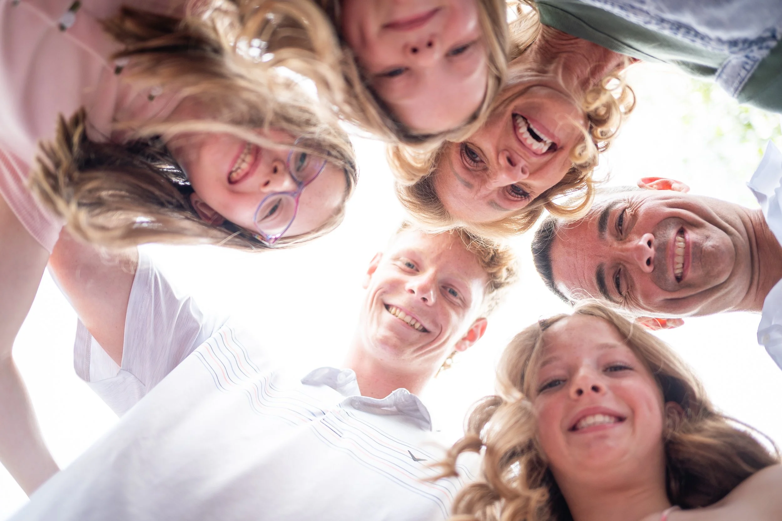 A group of smiling people and children looking down into the camera, taken from below.