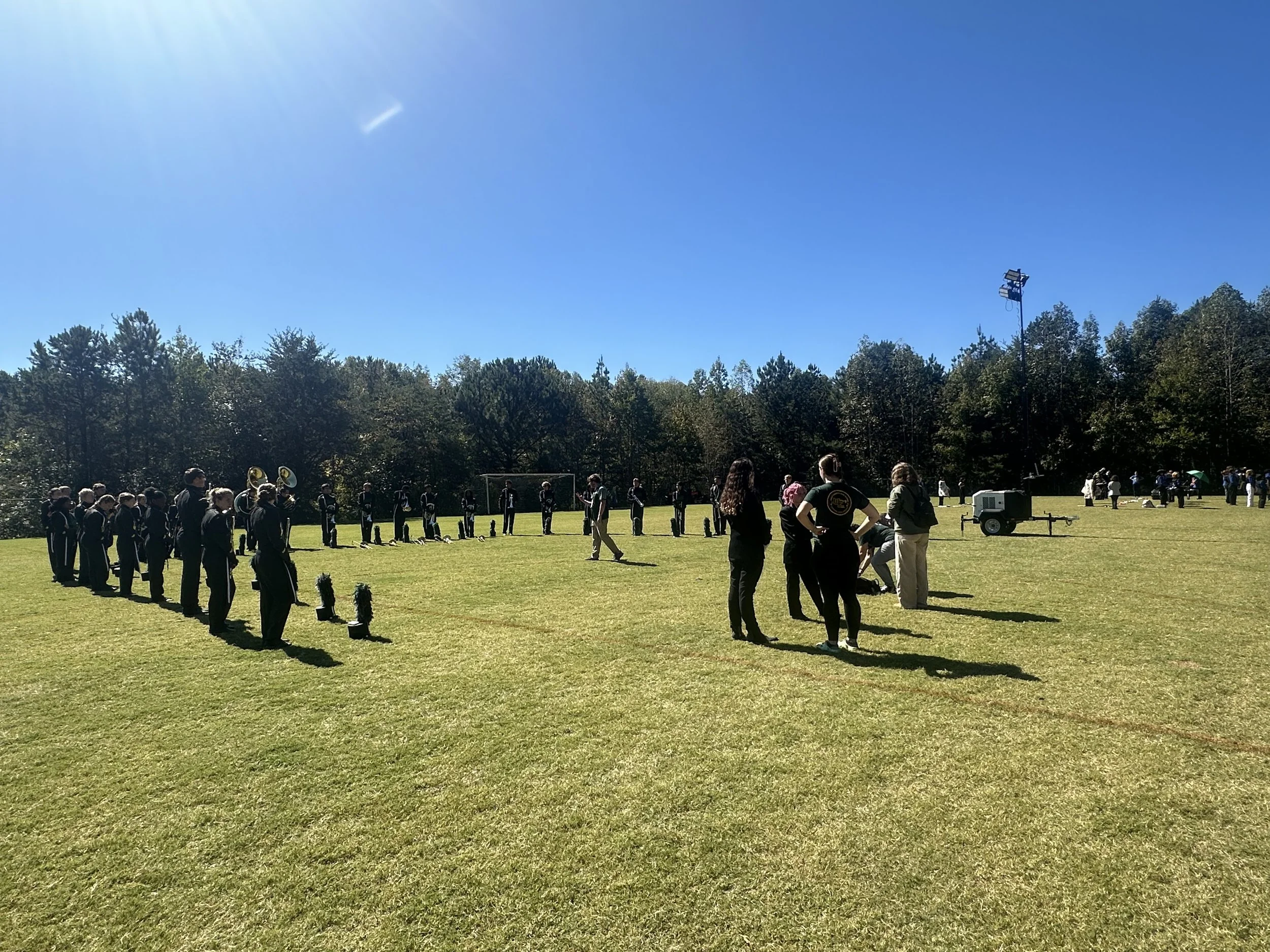 band warming up in a half circle in a grassy field at a competition