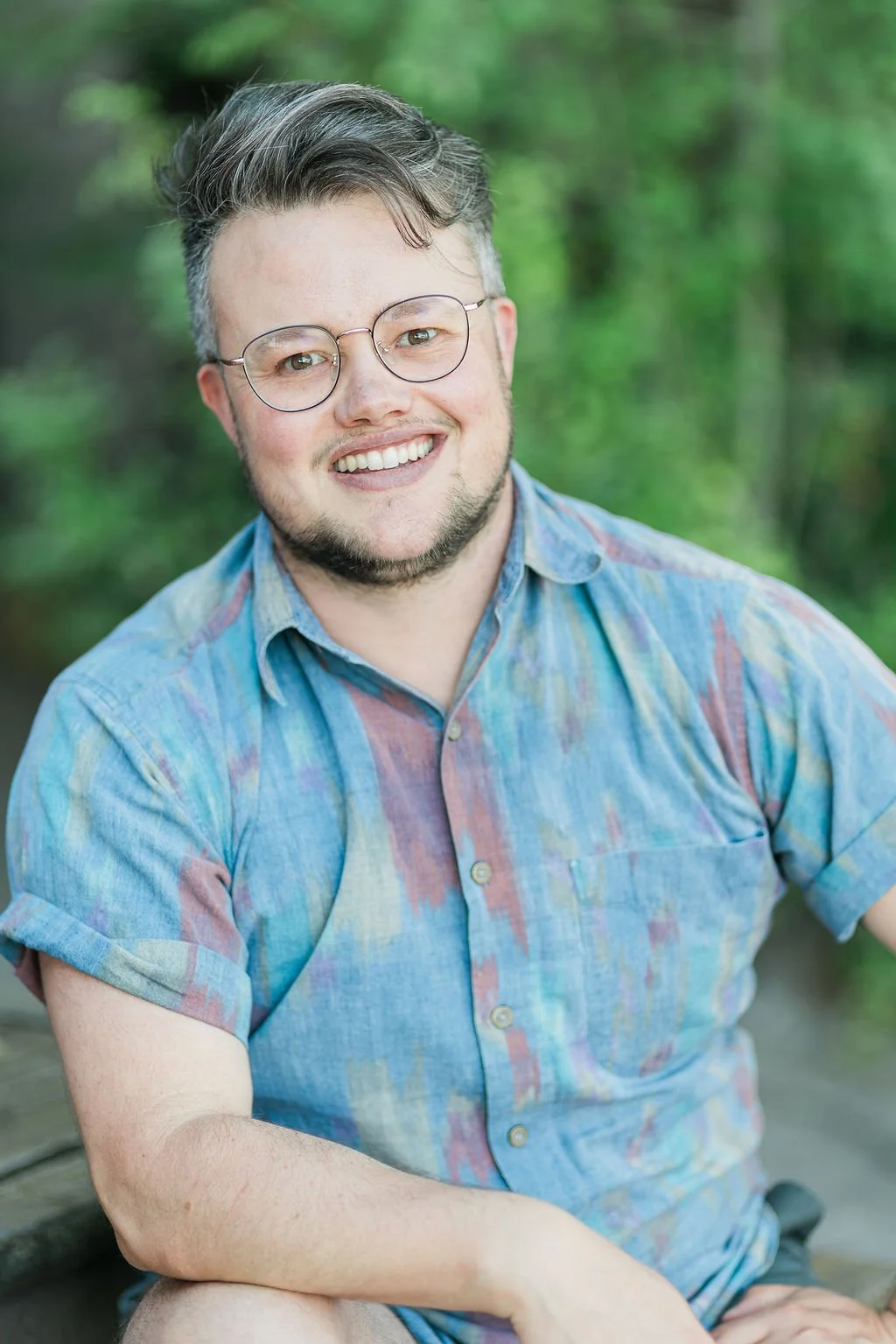 Rainer smiling at camera wearing glasses and a vintage collared shirt.