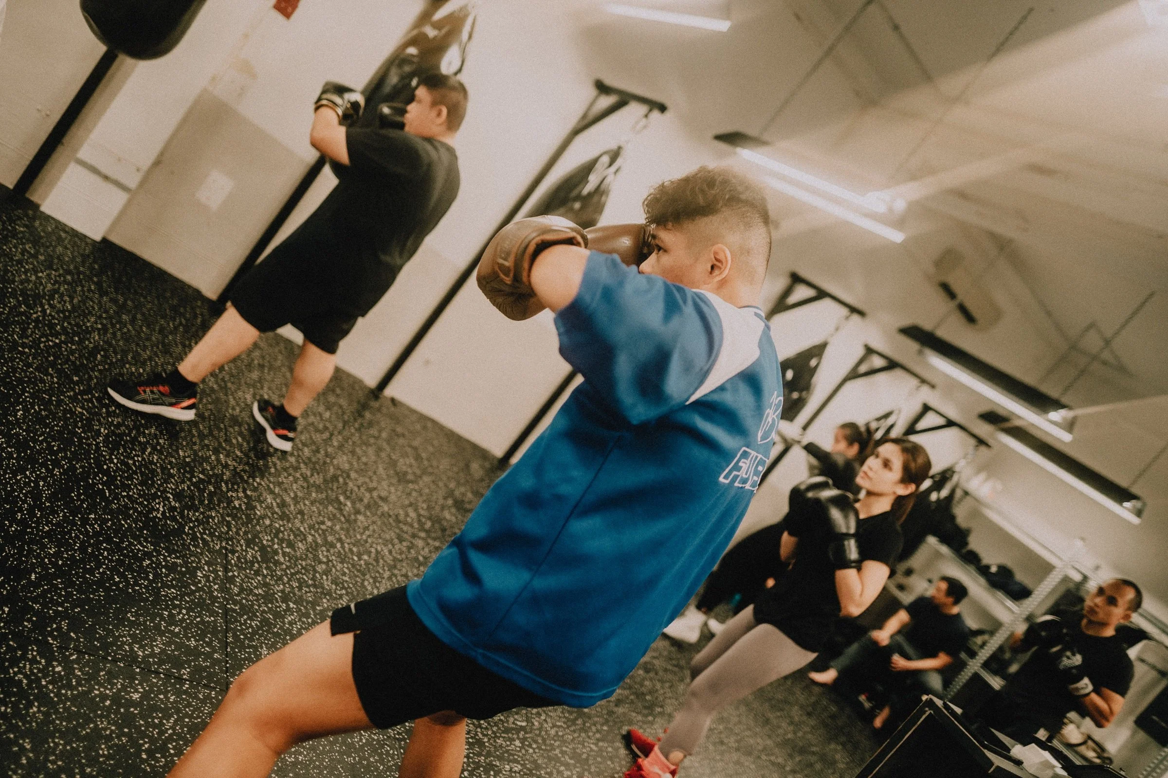 Members training in a boxing group class with heavy bags at Sweat Science Studio boxing gym in Clarke Quay Singapore