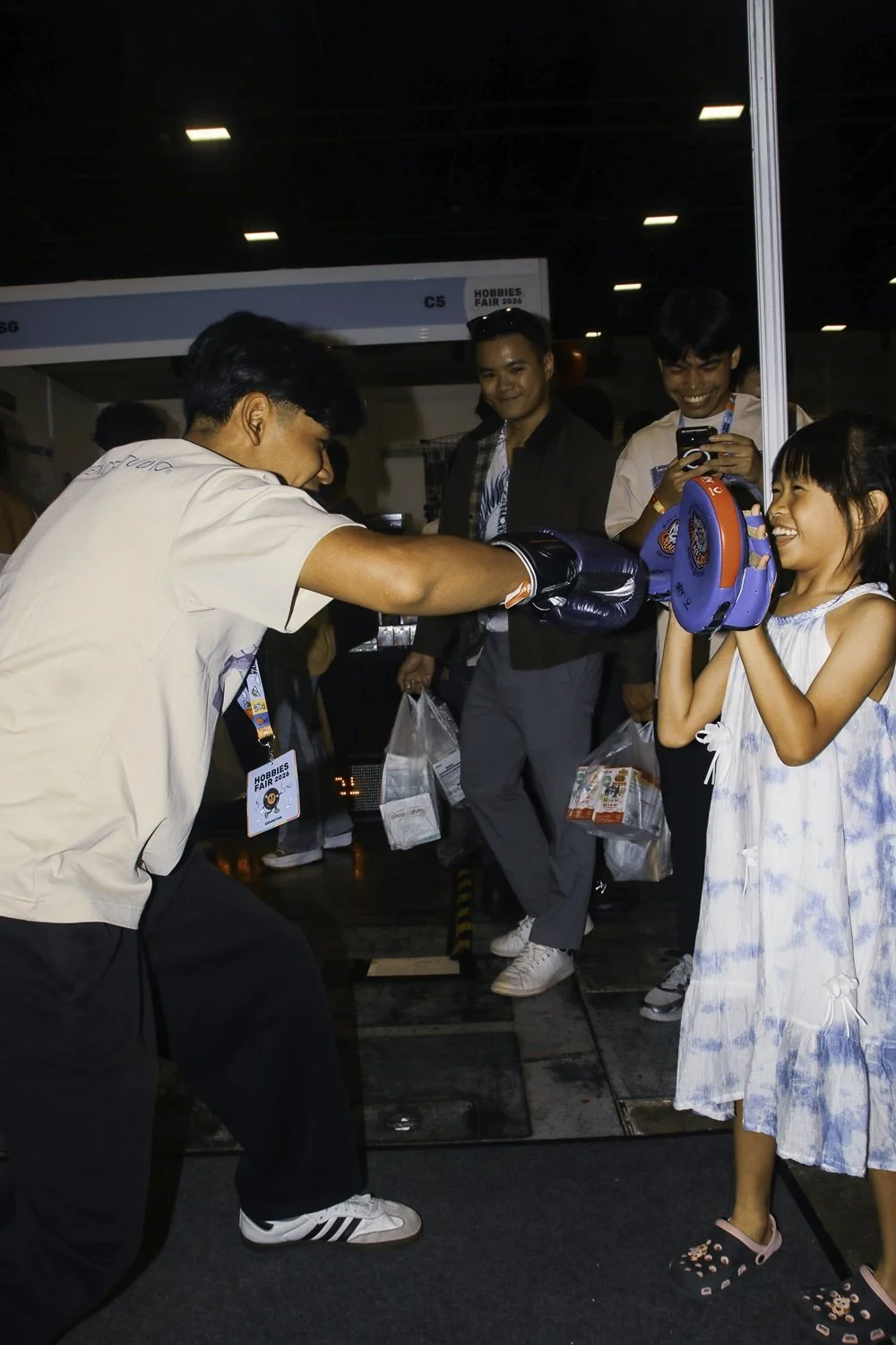 Coach holding punching pads for young girl during kids boxing session at Sweat Science Studio, Singapore