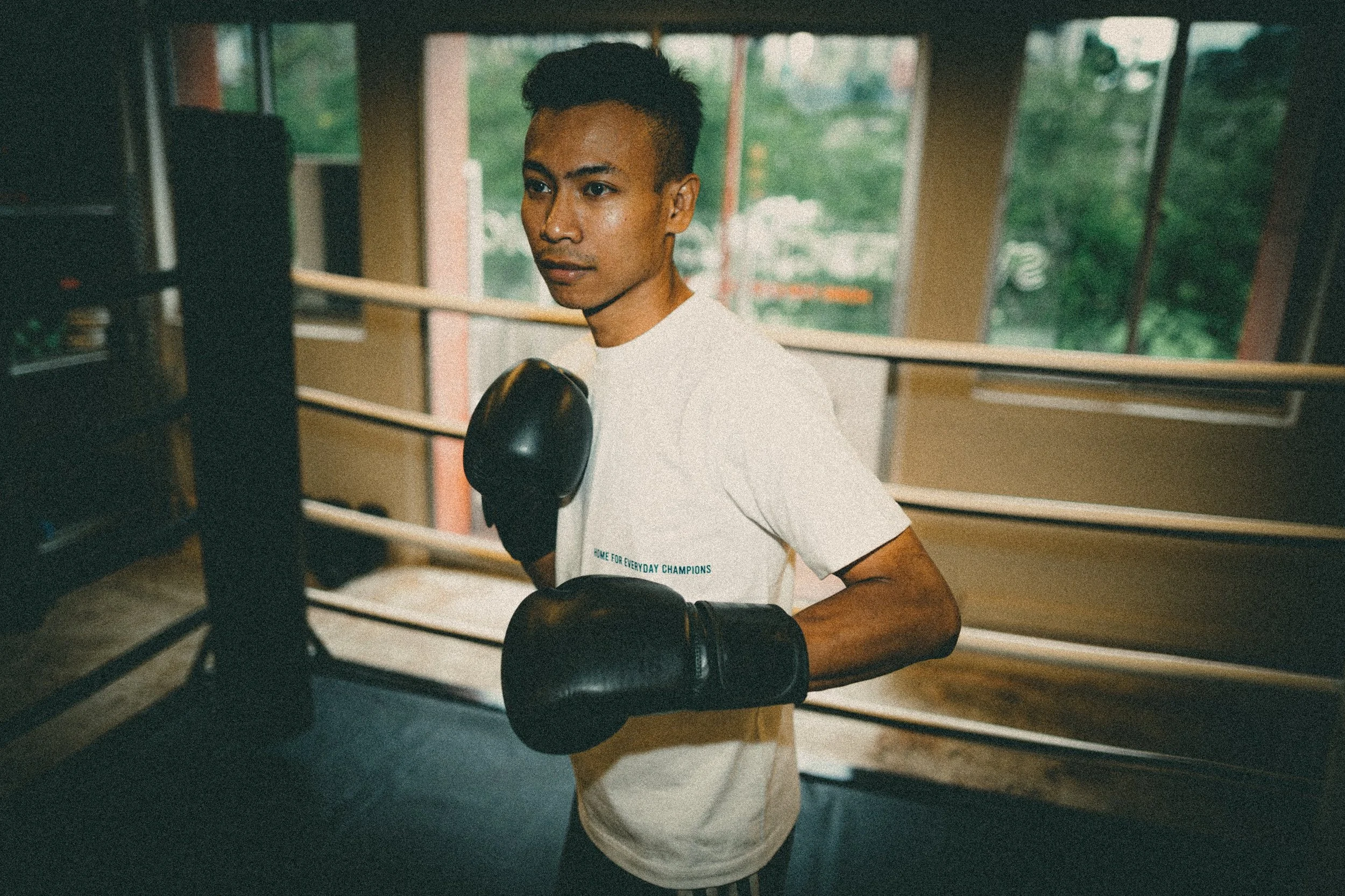 Coach Hafiz, national boxing champion and head coach at Sweat Science Studio, standing in the boxing ring in black boxing gloves.
