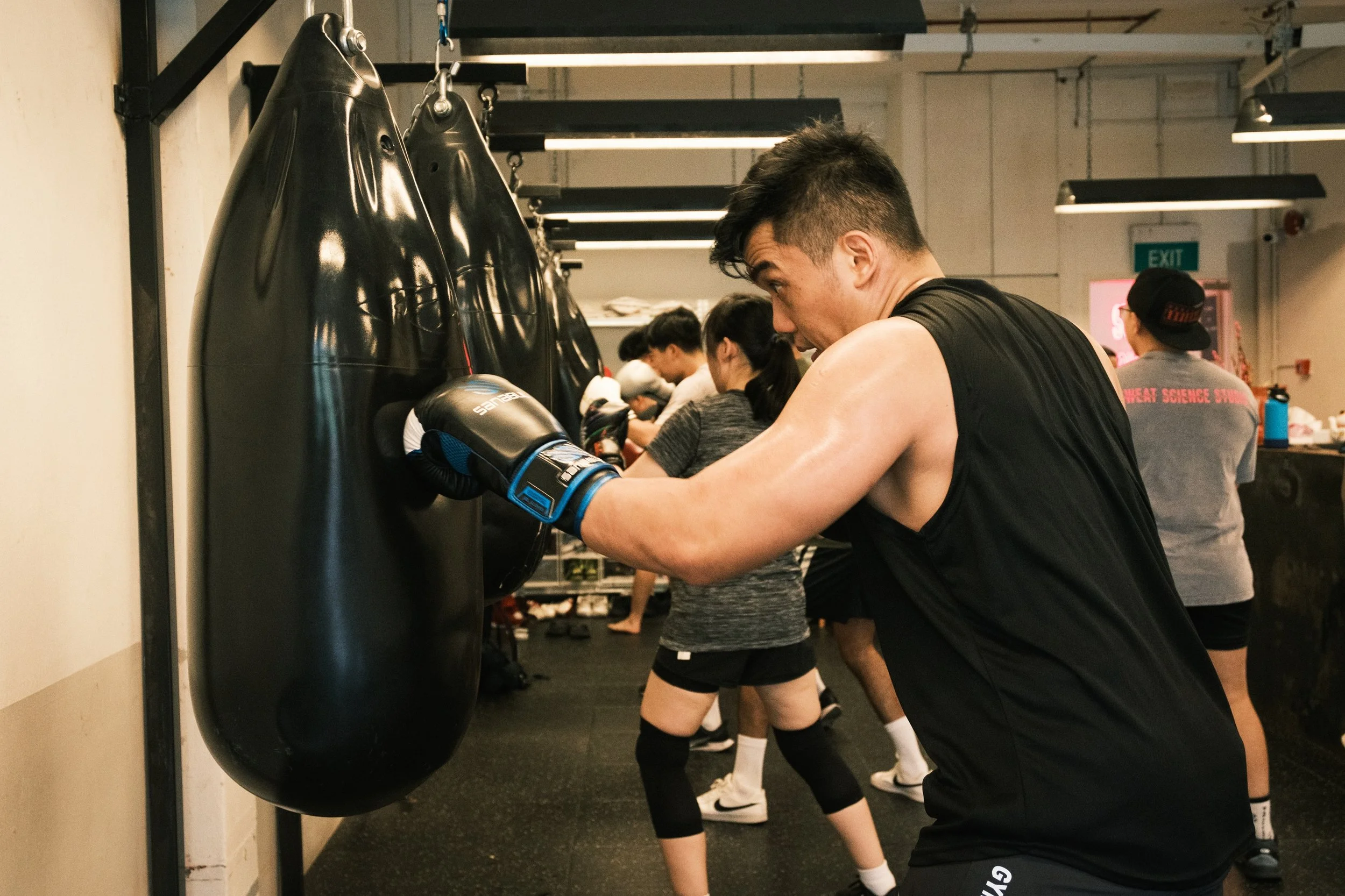 Man throwing a cross punch on a teardrop boxing bag during a group class at Sweat Science Studio, a boxing gym in Clarke Quay, Singapore