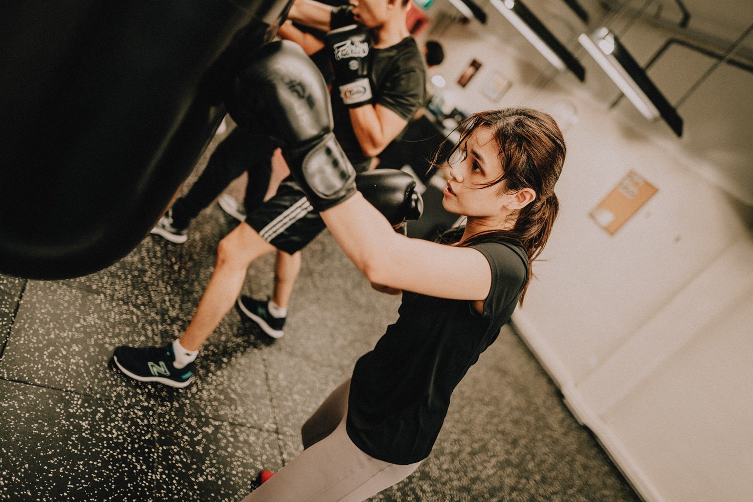 Woman punching heavy bag during boxing training at Sweat Science Studio Singapore