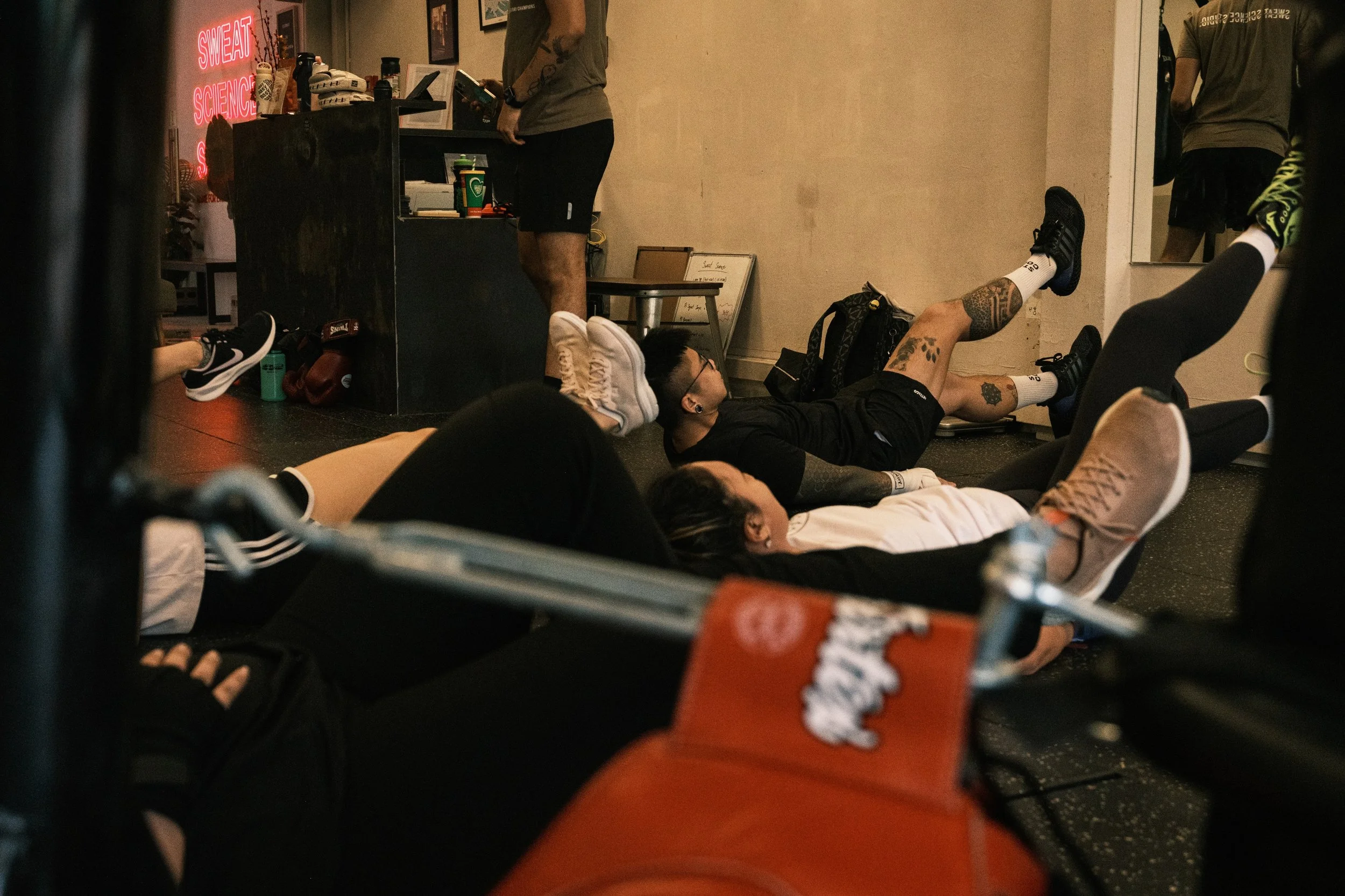 Members doing core conditioning exercises on the gym floor at Sweat Science Studio boxing gym in Clarke Quay, Singapore