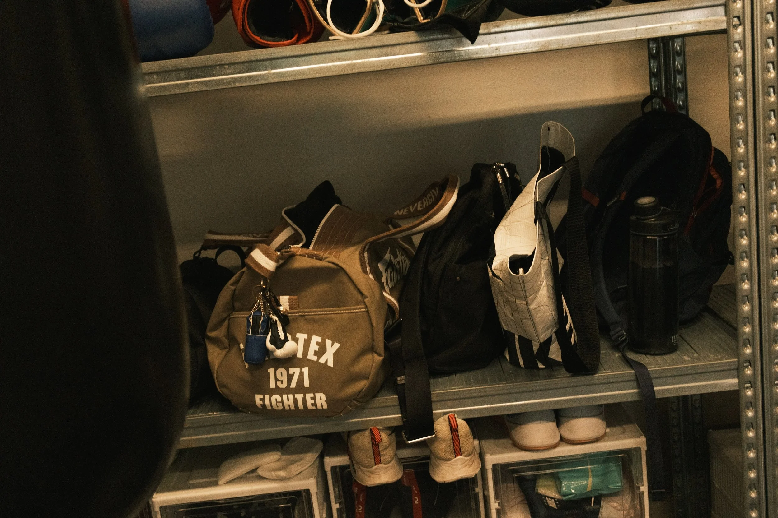 Boxing gym gear shelf with Fairtex 1971 Fighter duffel bag and training bags at Sweat Science Studio Singapore