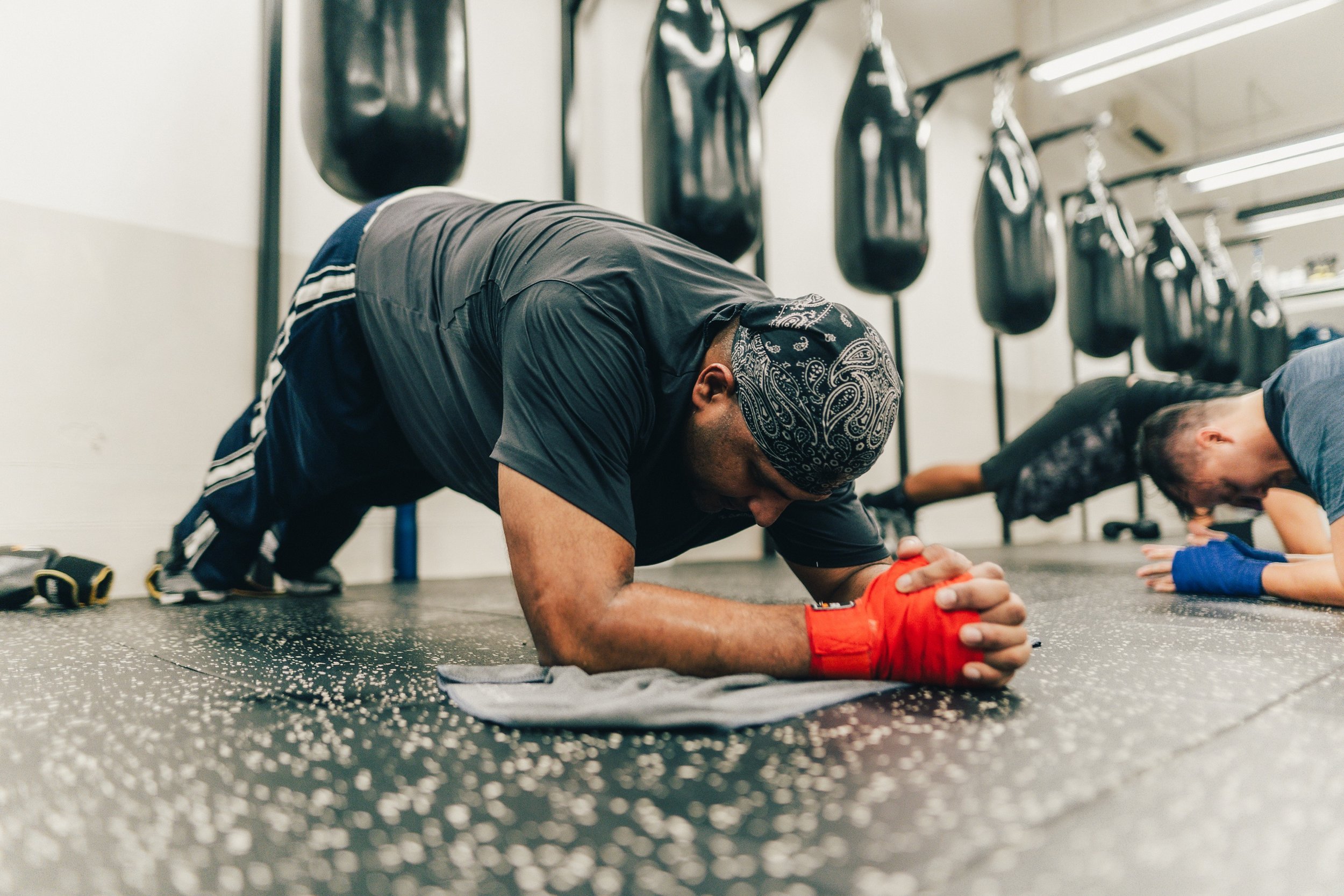 Members doing forearm planks with boxing hand wraps during a conditioning class at Sweat Science Studio, Clarke Quay