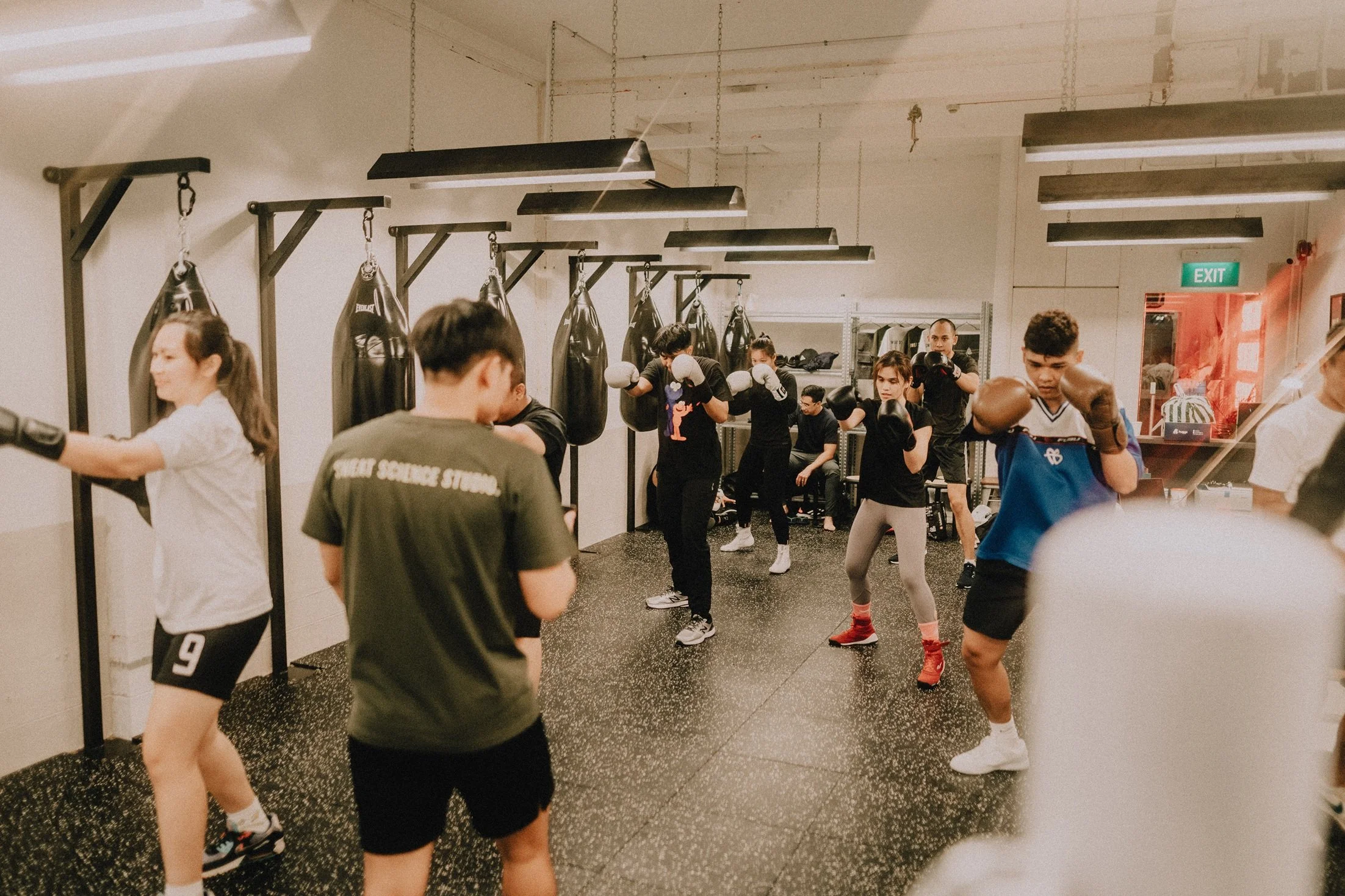 Group boxing class hitting heavy bags at Sweat Science Studio, a boutique boxing gym in Clarke Quay Singapore