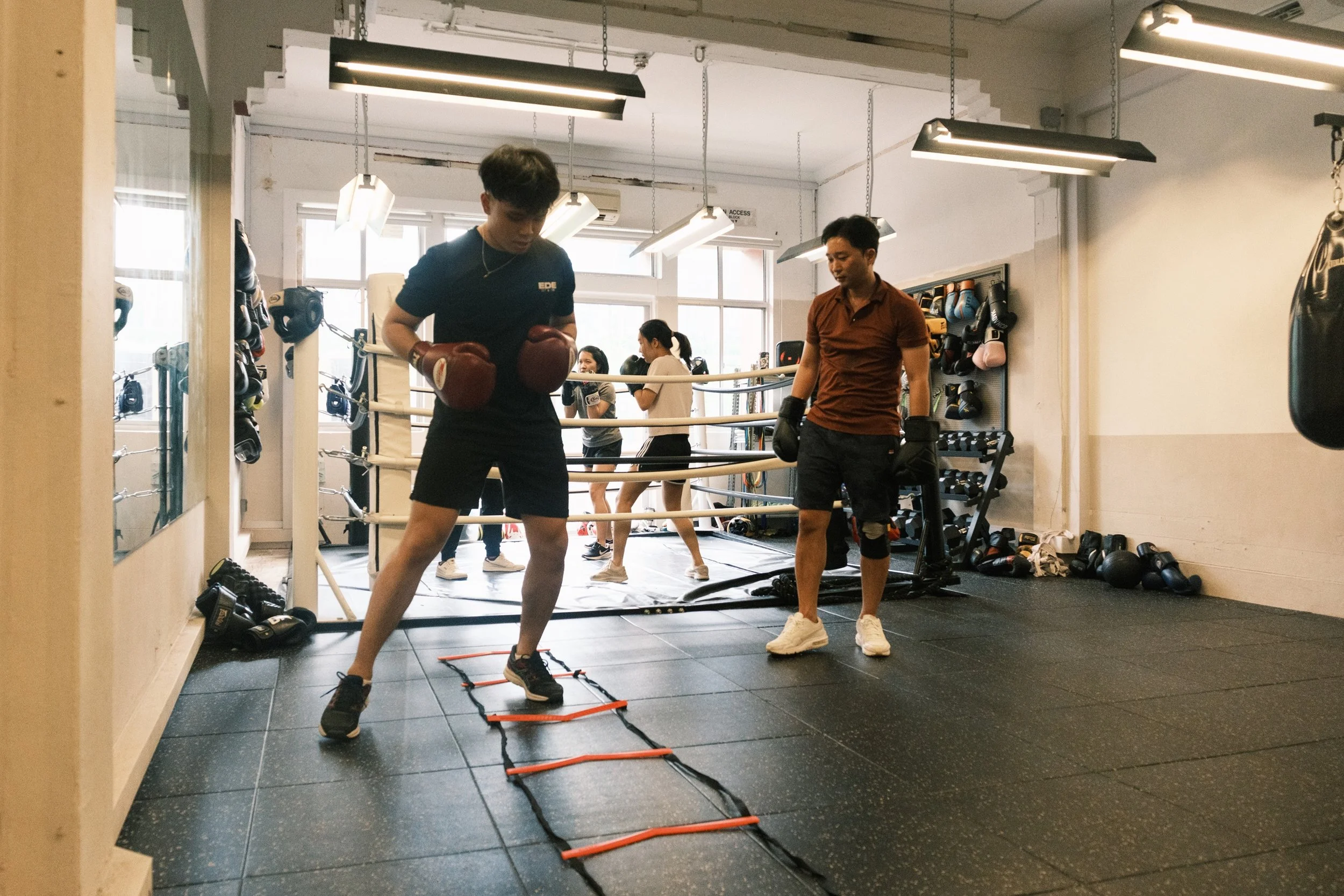 Boxer practicing footwork on an agility ladder during a boxing training session at Sweat Science Studio, Clarke Quay Singapore