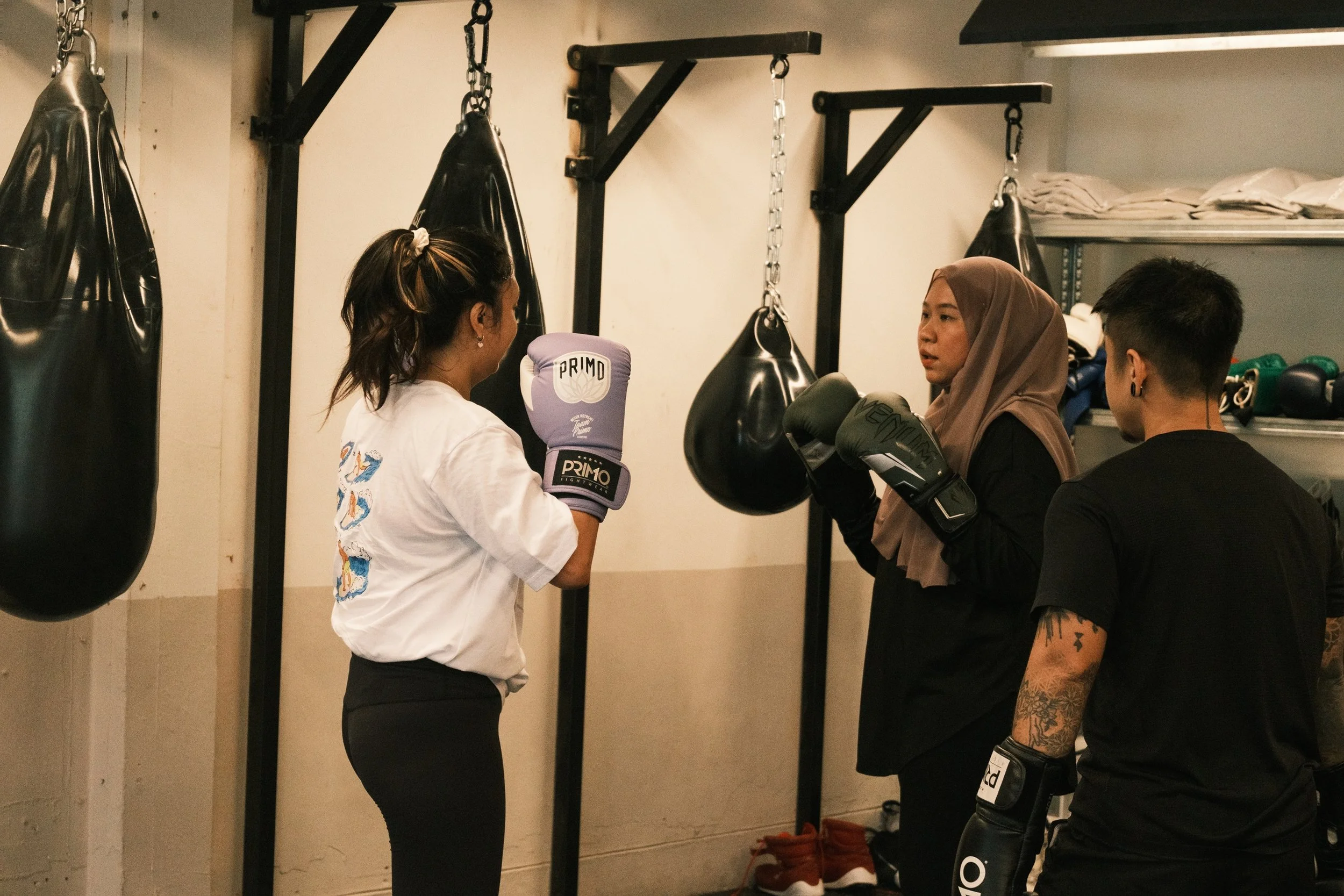 Two women in boxing gloves practising sparring drills at Sweat Science Studio, a boutique boxing gym in Singapore