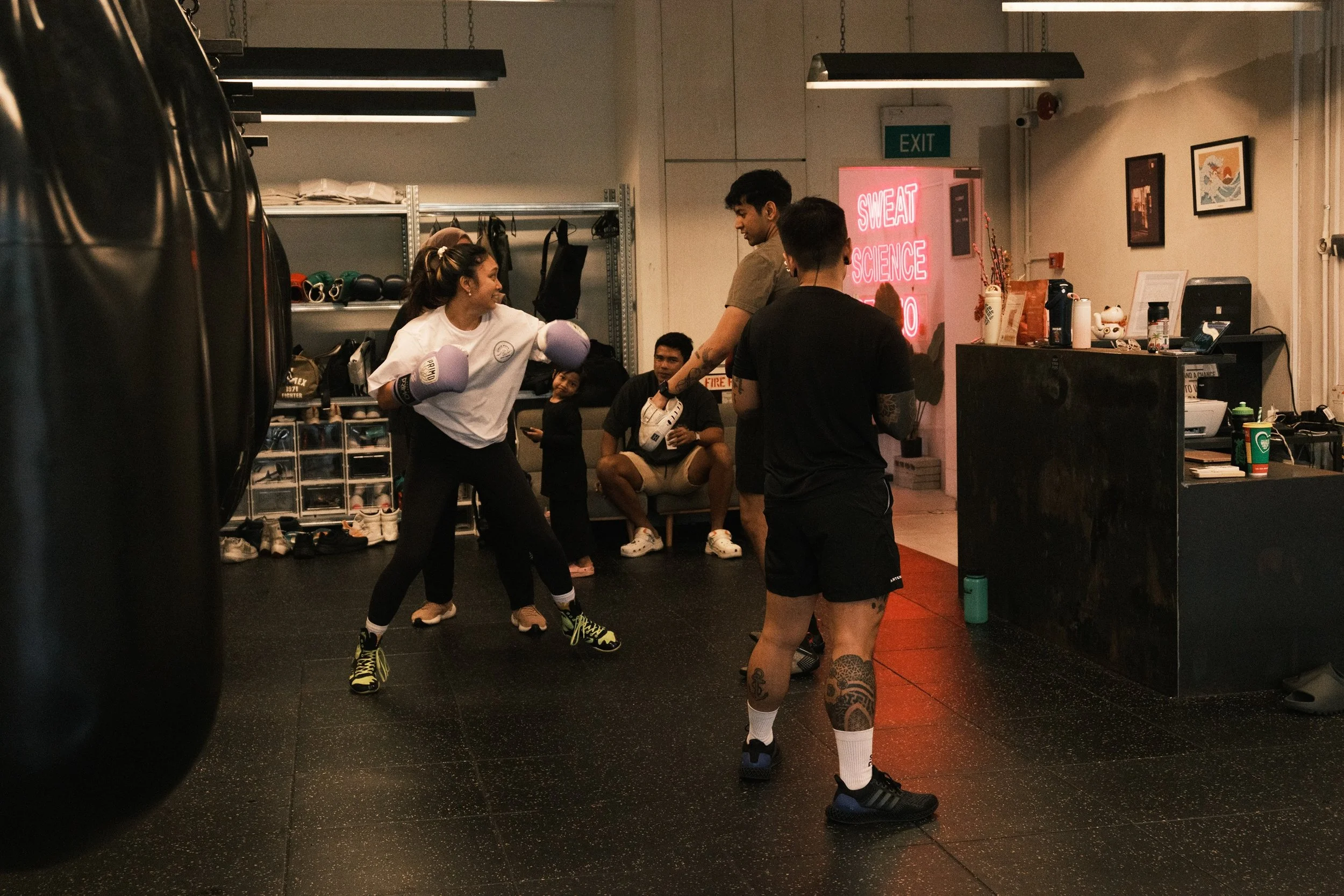 Female boxer in purple gloves training with a coach at Sweat Science Studio boxing gym in Singapore
