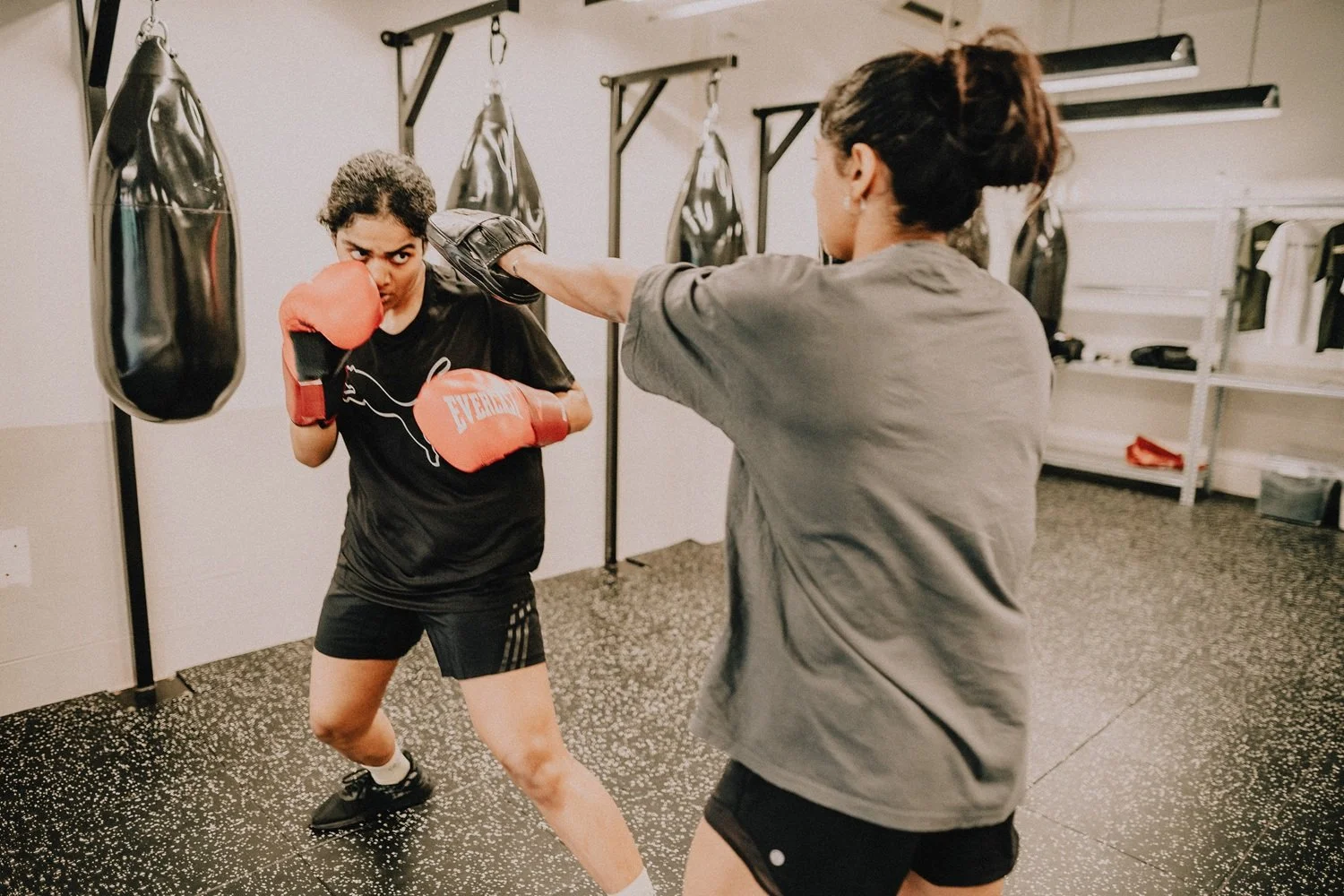 Two women sparring with boxing gloves during partner drill class at Sweat Science Studio Singapore