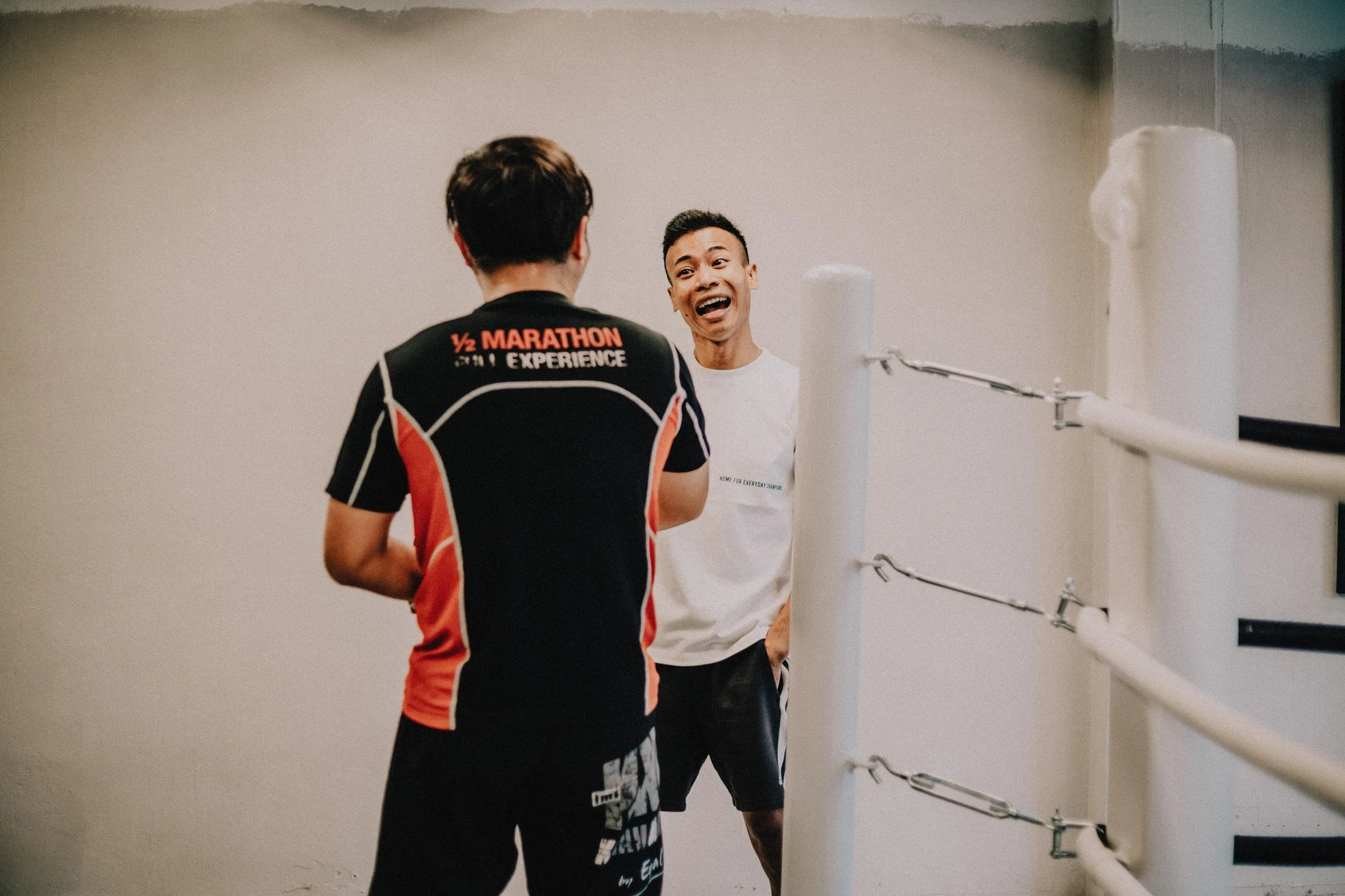 Boxing coach and member sharing a laugh during a personal training session at Sweat Science Studio boxing gym in Singapore
