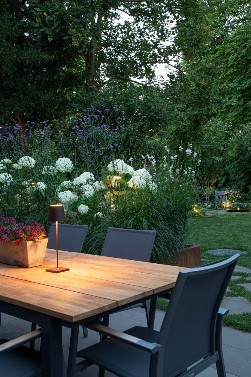 Sitzplatz mit Esstisch im bepflanzten Garten