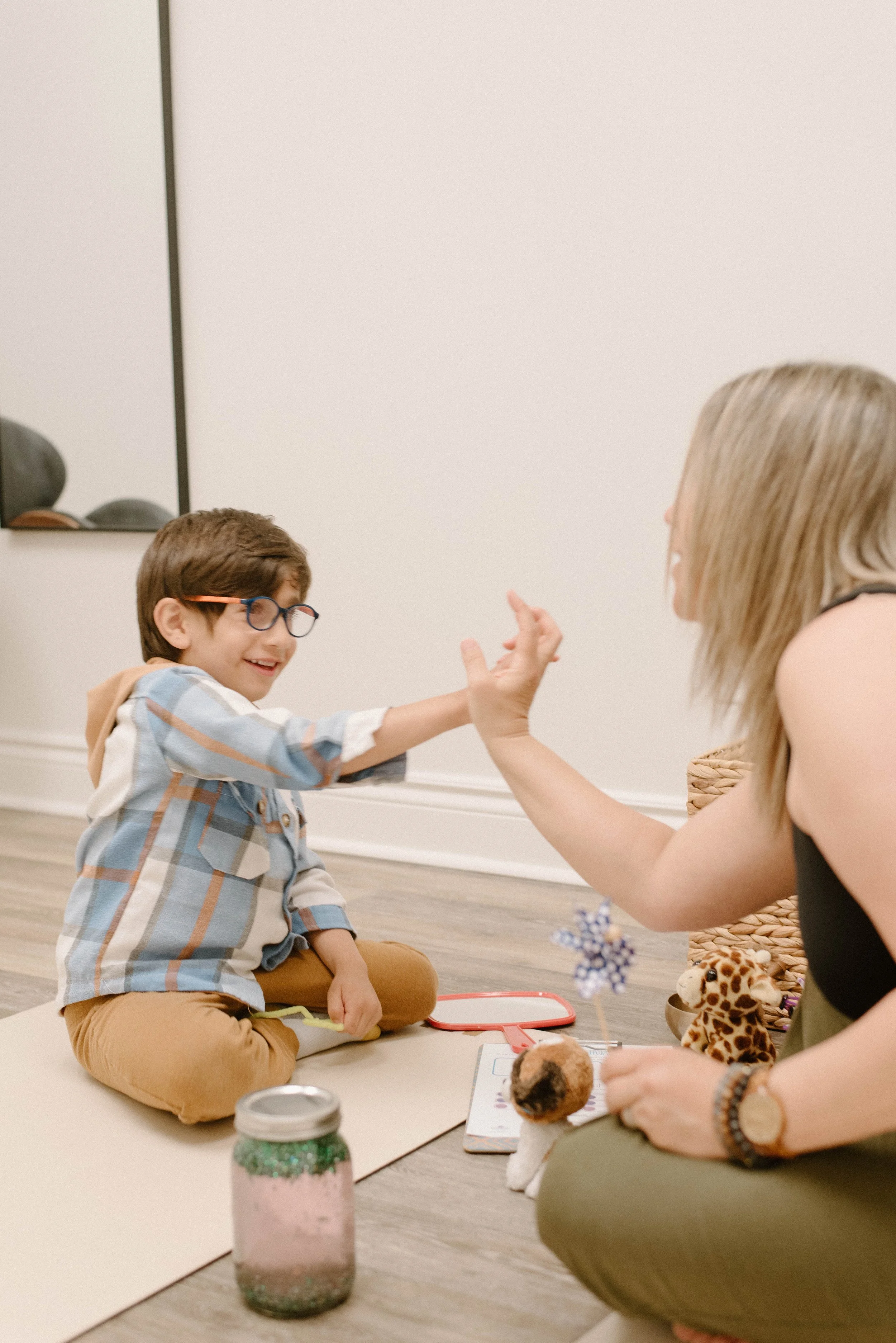 CEO Melissa with 1:1 child client in session smiling and high fiving.