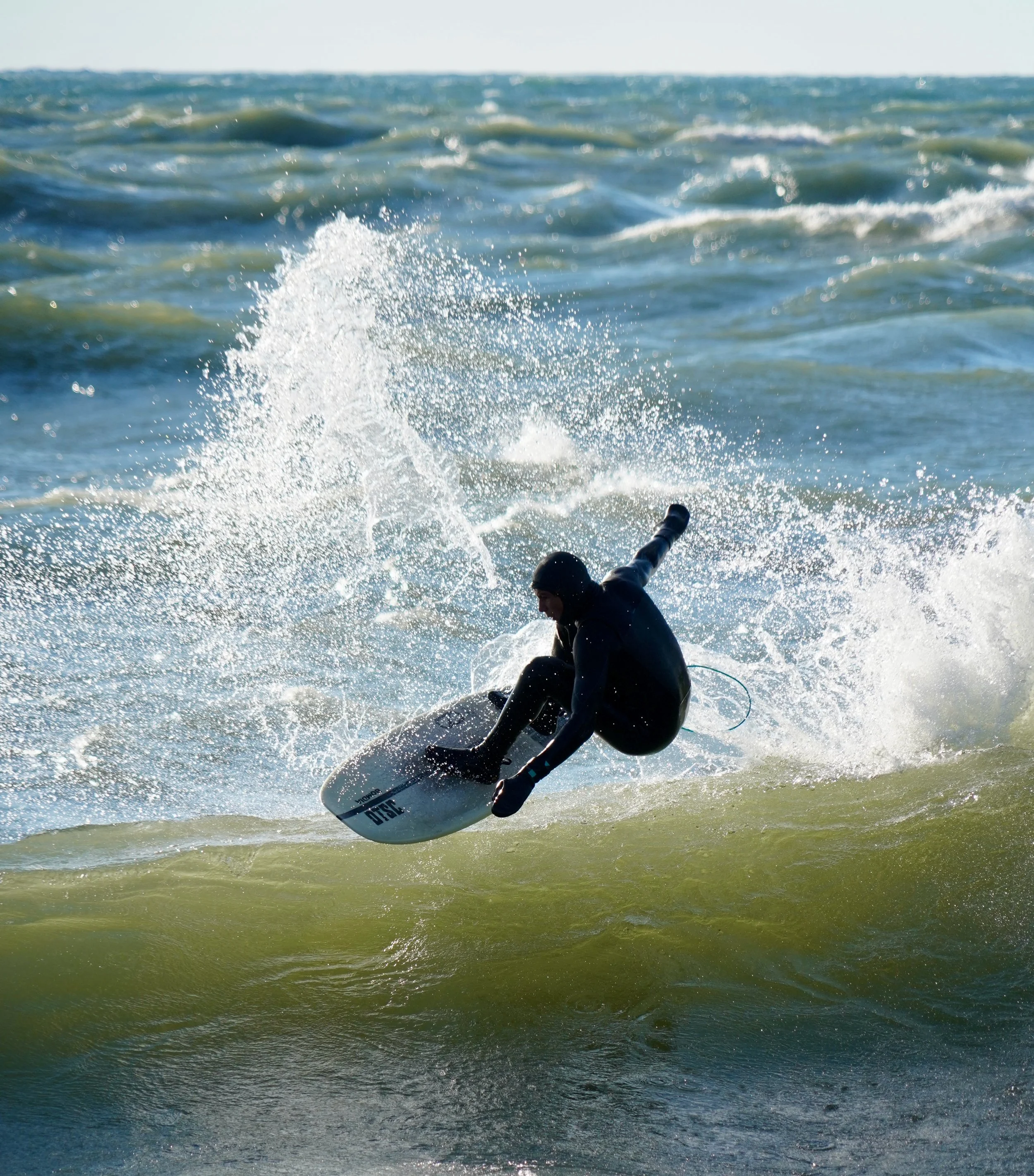 Surfer in a wetsuit performing a maneuver on a wave in the ocean.
