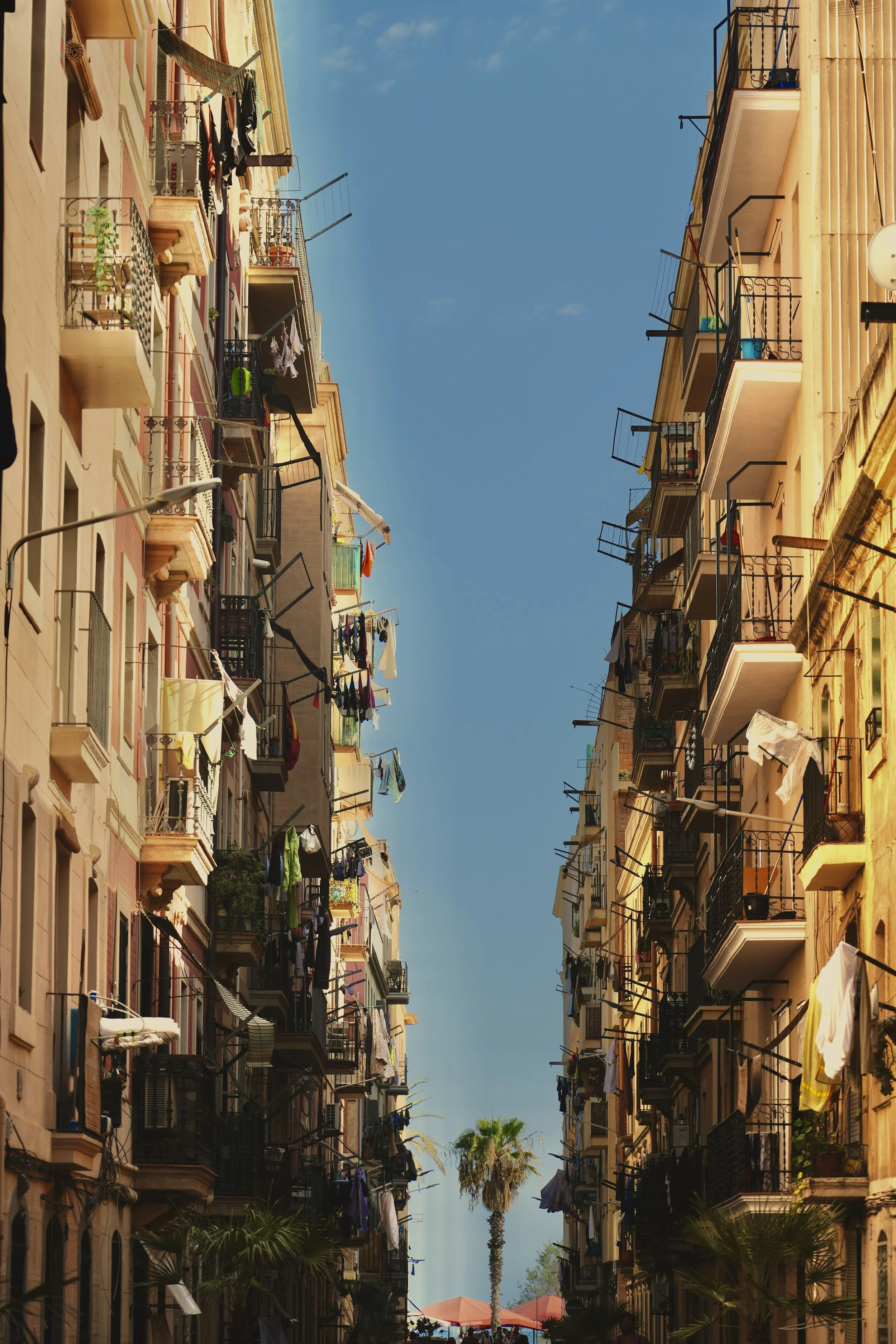 Narrow street with balconies and hanging laundry between buildings
