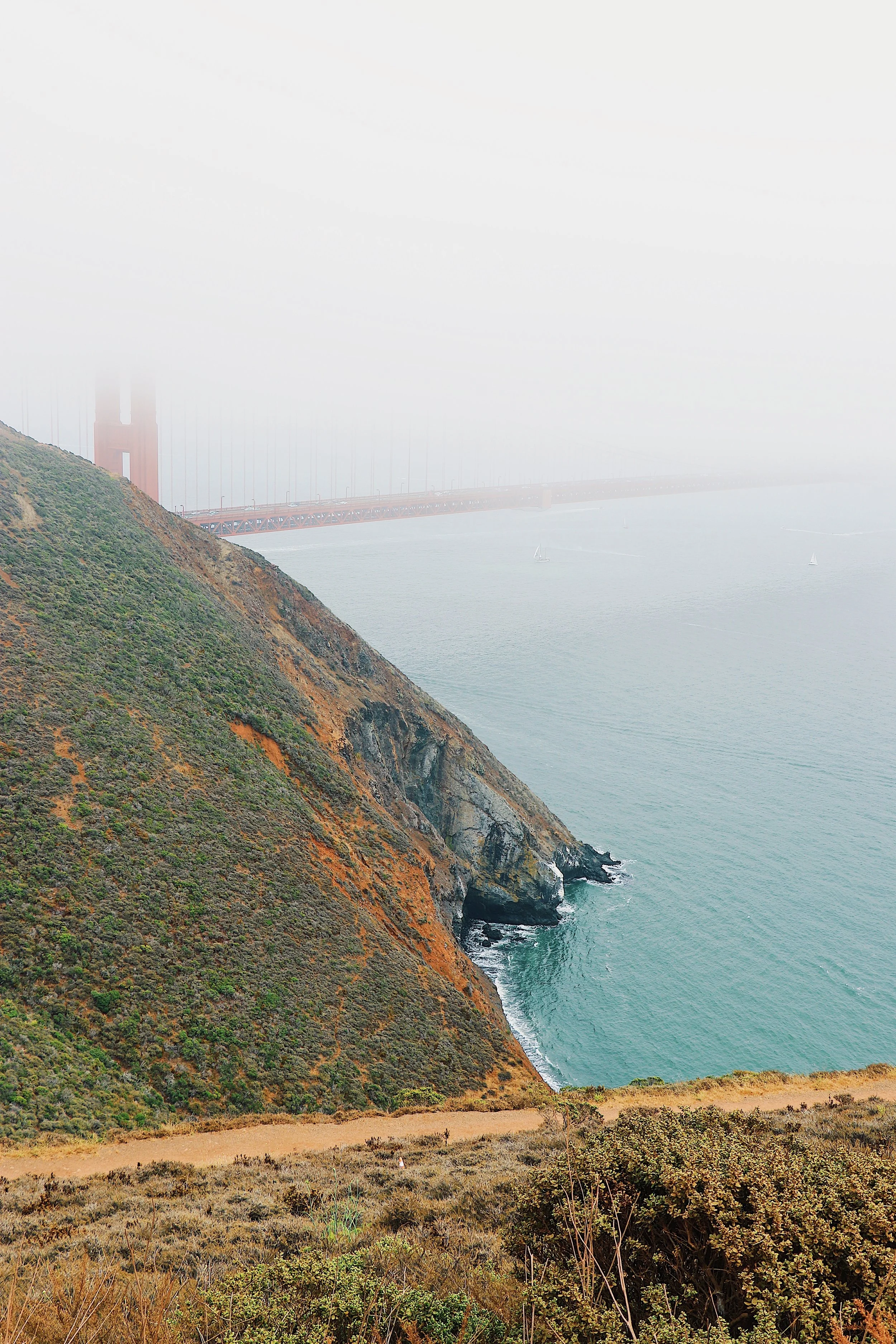 Fog-covered Golden Gate Bridge, coastal cliffs, and ocean