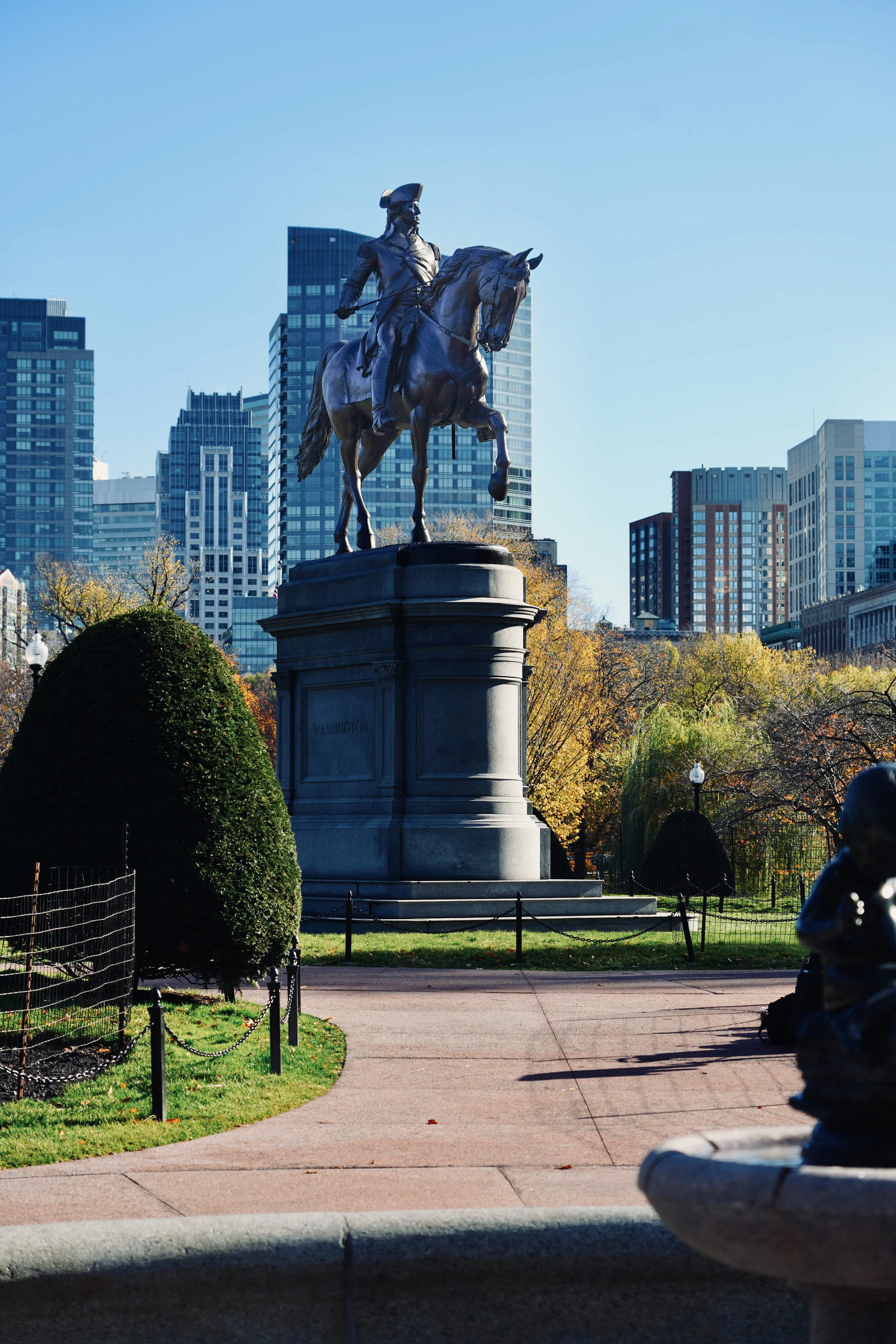 Equestrian statue in city park with skyscrapers and trees