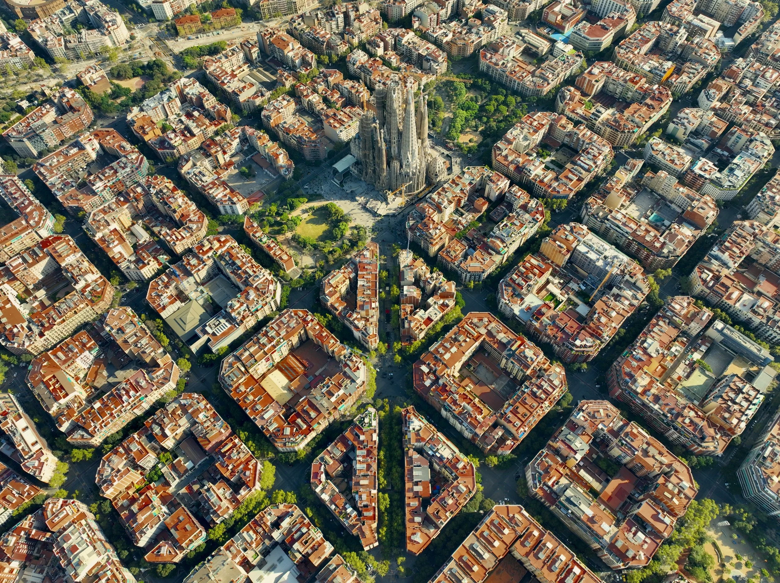 Aerial view of a city with a grid-like street pattern and a large, unfinished cathedral in the center.
