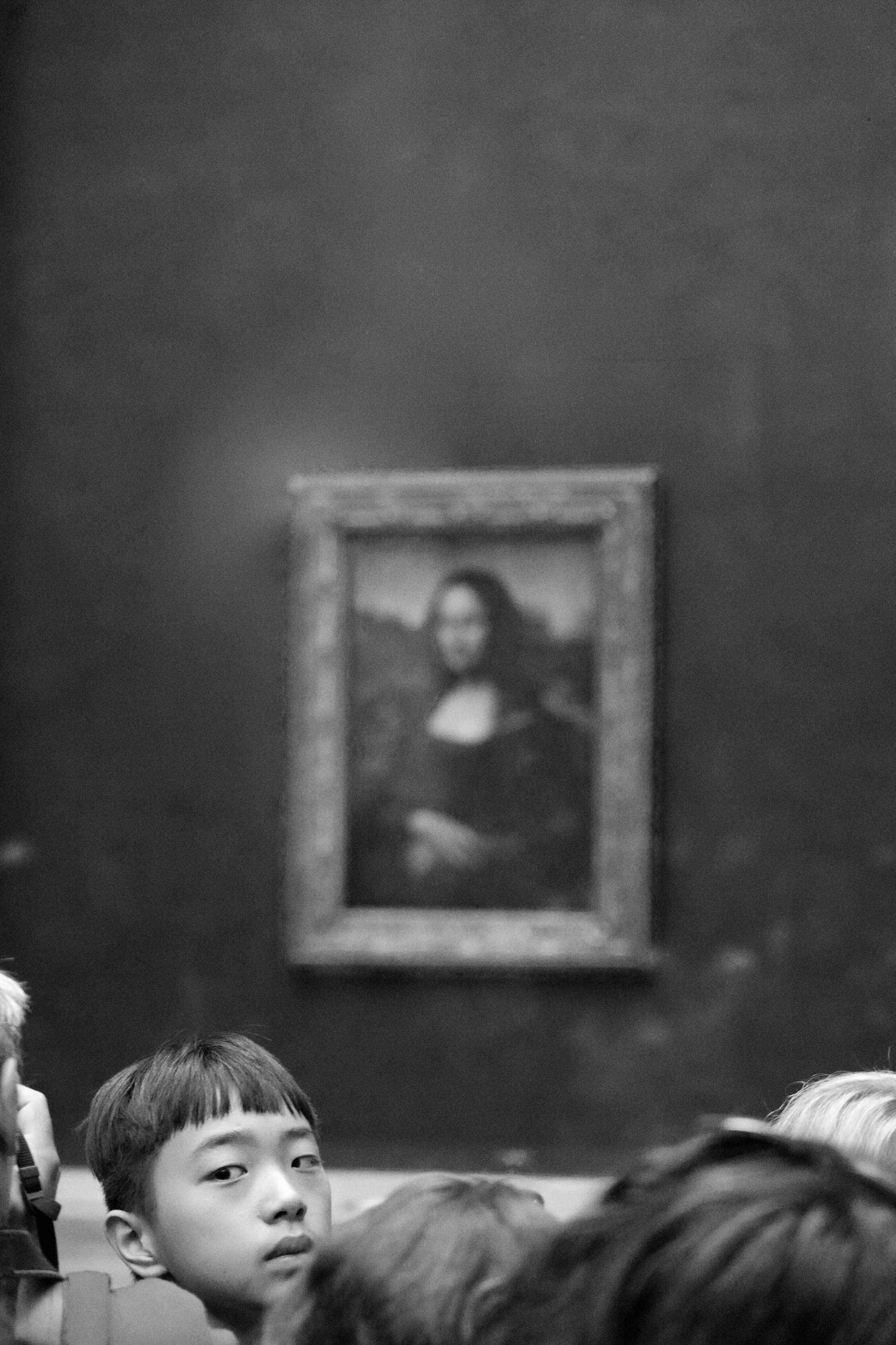 Black and white photo of a person in front of a blurred Mona Lisa painting with a crowd.