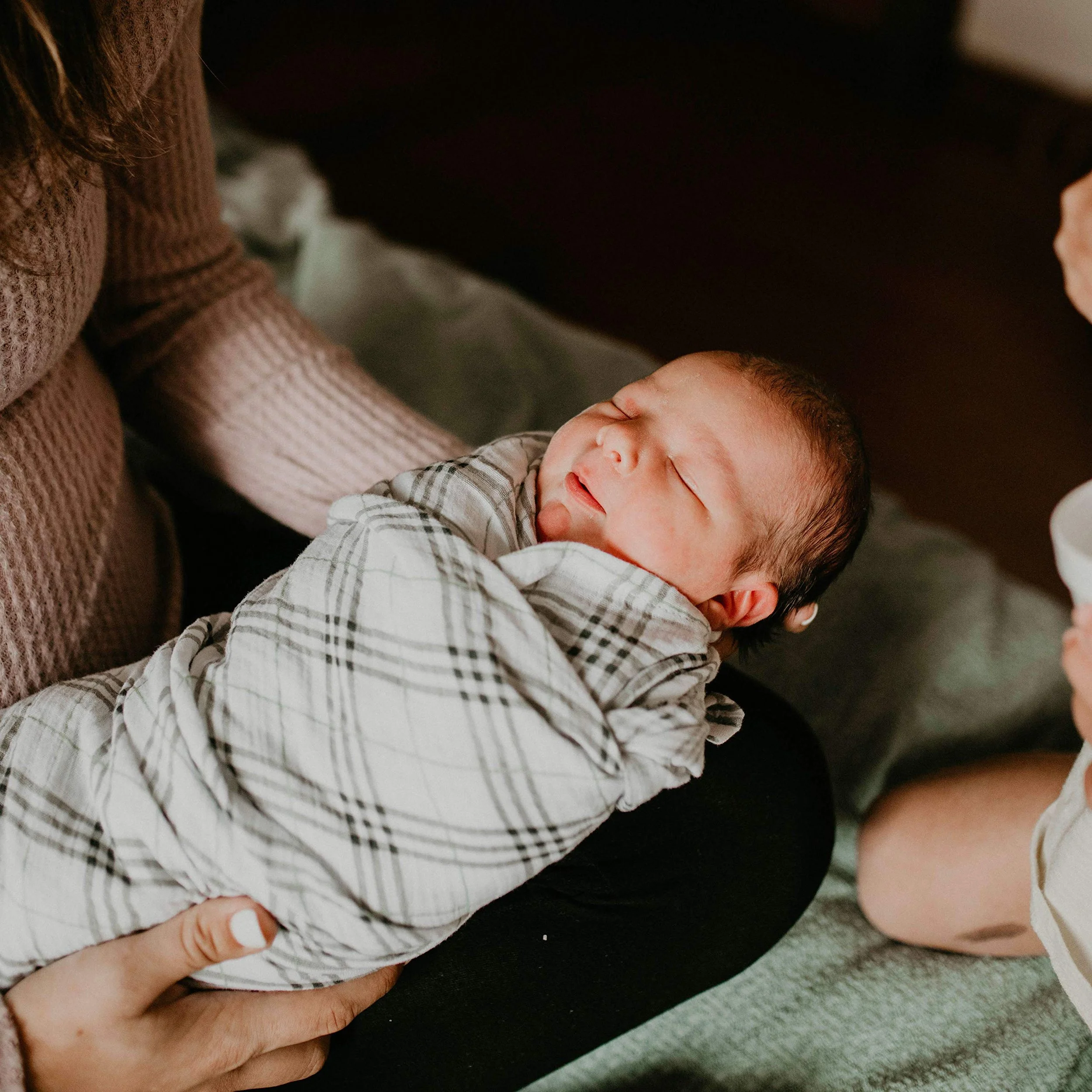 Newborn Care Specialist holding swaddled newborn baby in South Tampa Nursery during overnight newborn care