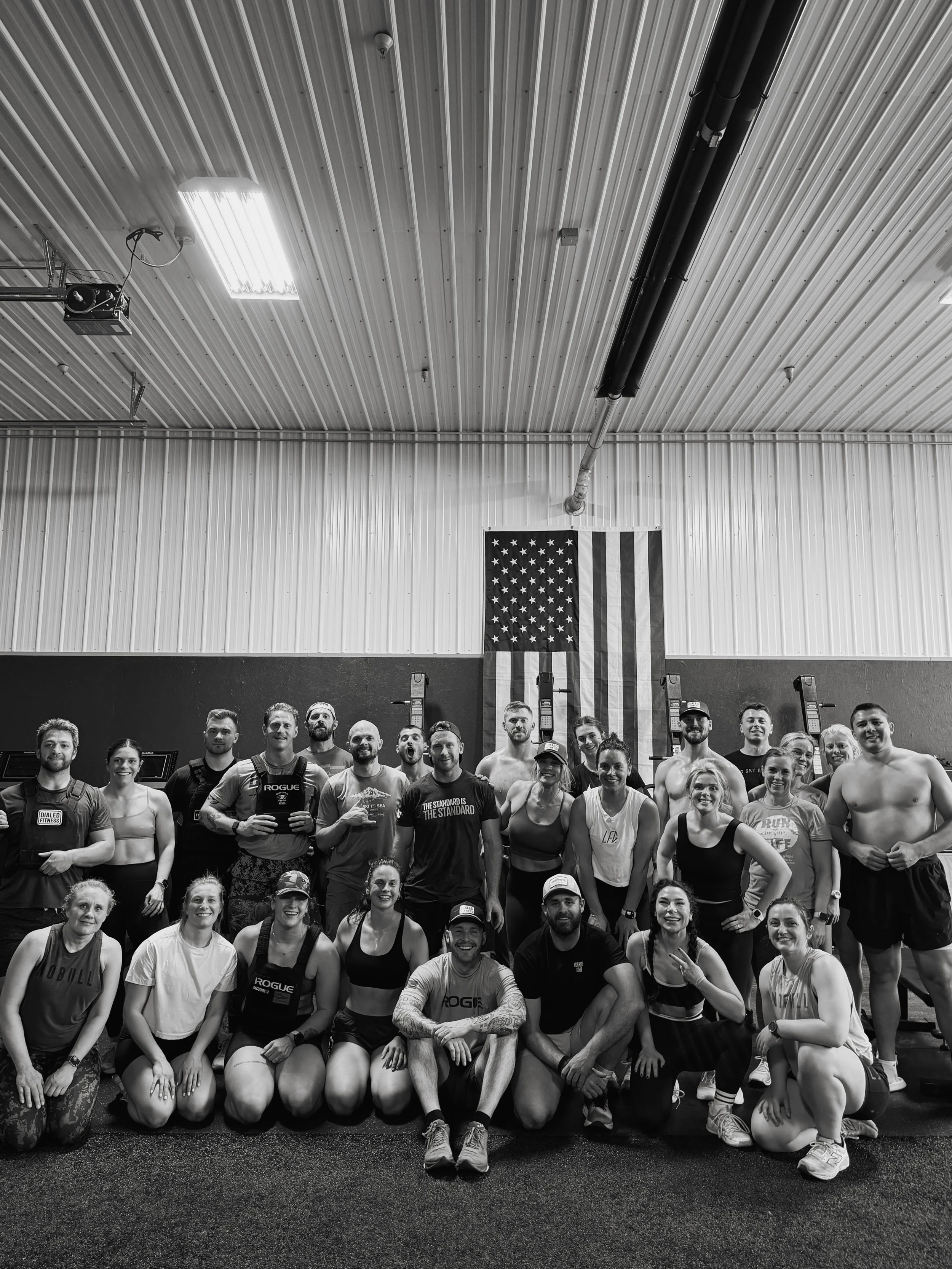 Blurred black and white photo of a person riding a skateboard, wearing white sneakers and shorts, in an indoor space.