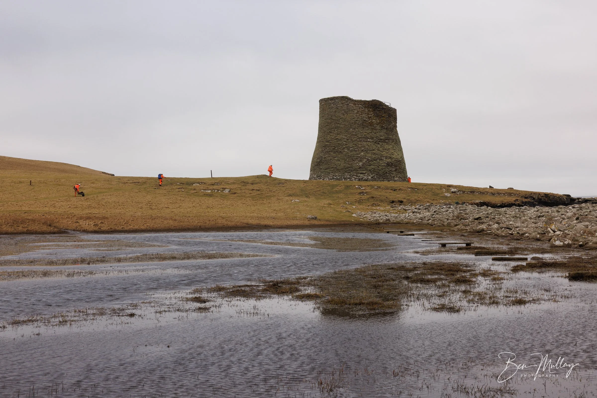 Historic Environment Scotland team in orange jackets arriving at Mousa Broch in Shetland