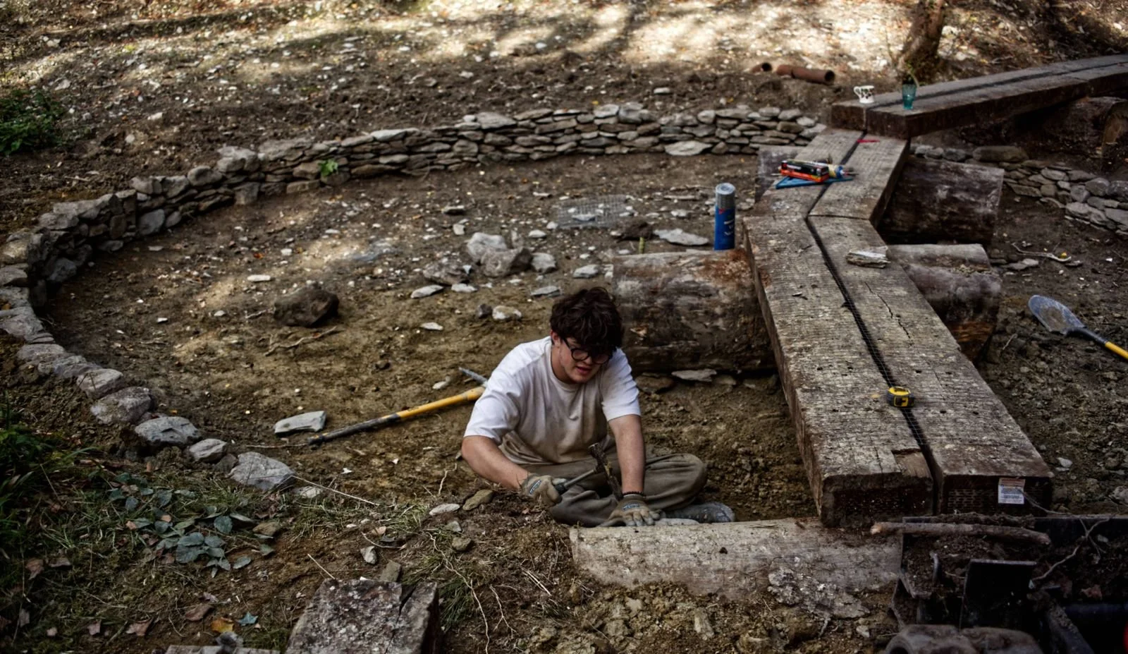 Work on ephemeral seasonal pond with circular drystone walling and boardwalk across garden feature