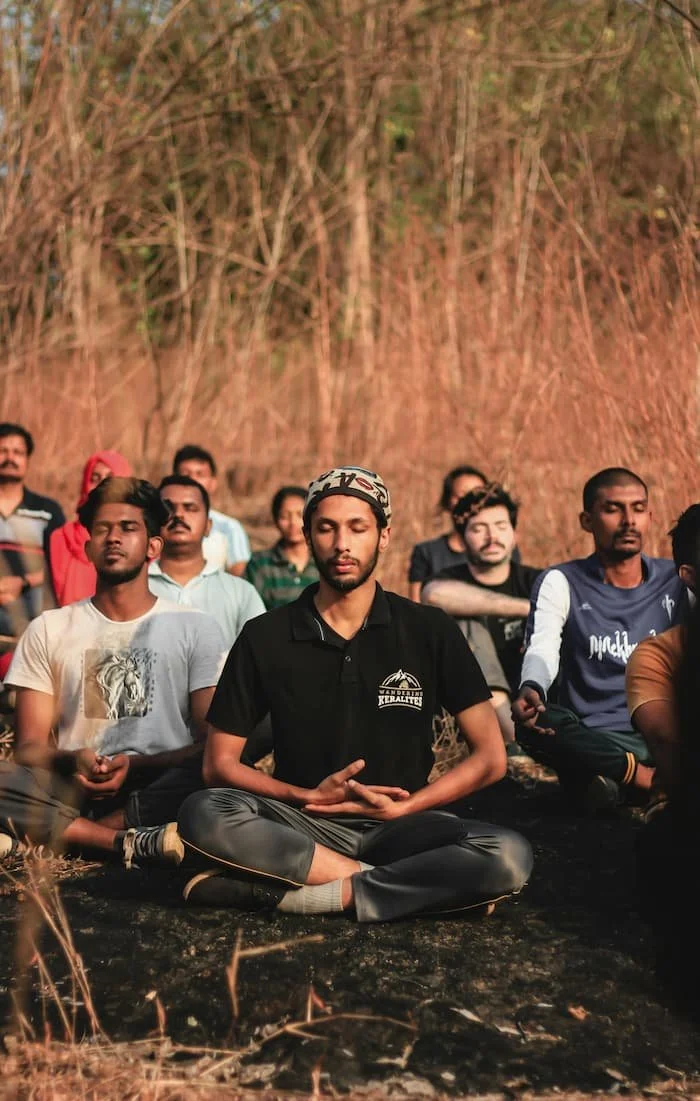 group of diverse people meditating outside in a nature setting
