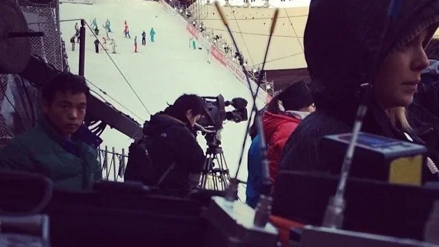 Film crew operating camera equipment on a snowy ski slope location