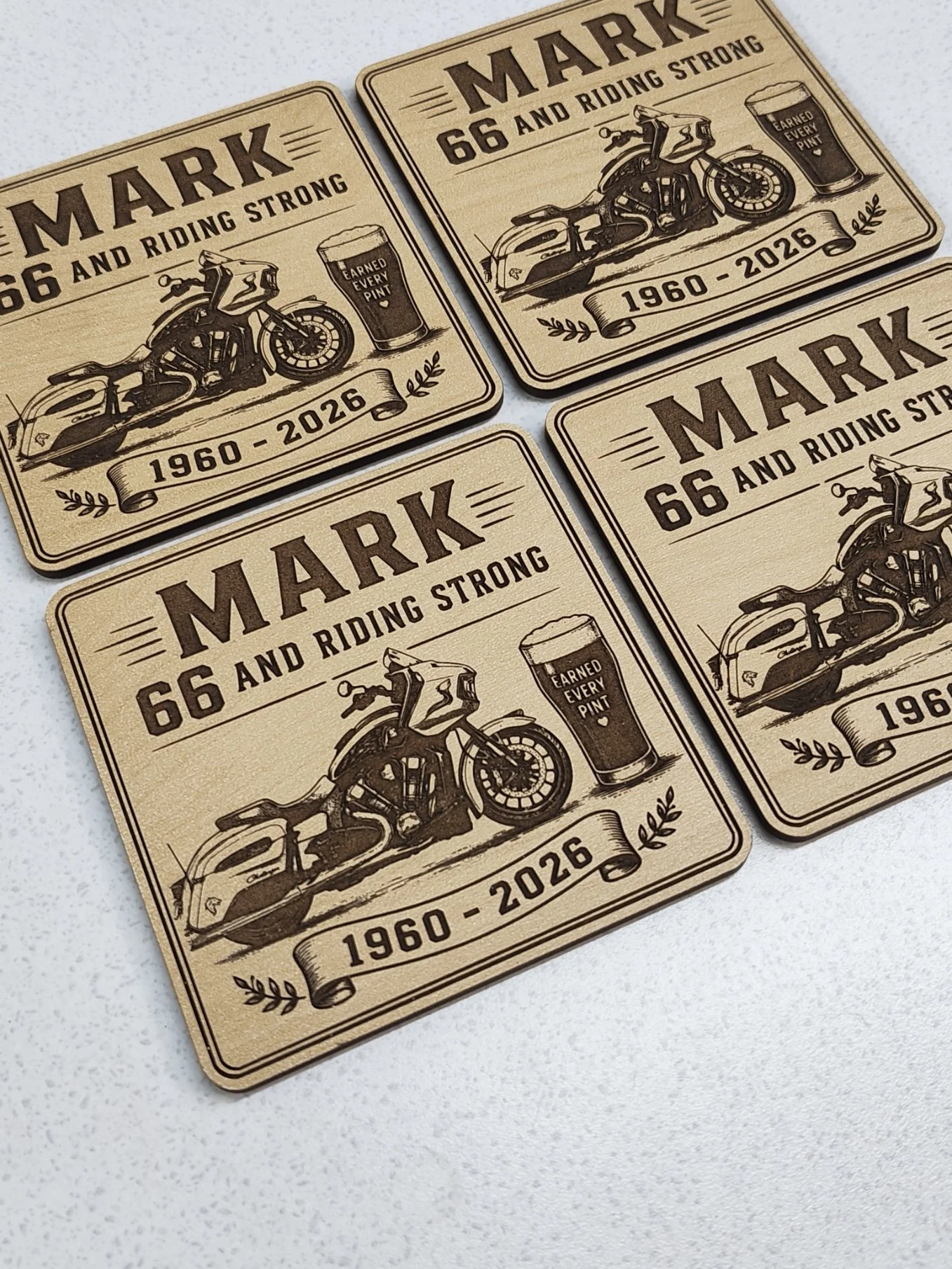 Set of four vintage-style wooden coasters with engraved designs celebrating motorcycling and beer, featuring a motorcycle, a pint of beer with the phrase 'Earned Every Pint', and the dates 1960-2026.