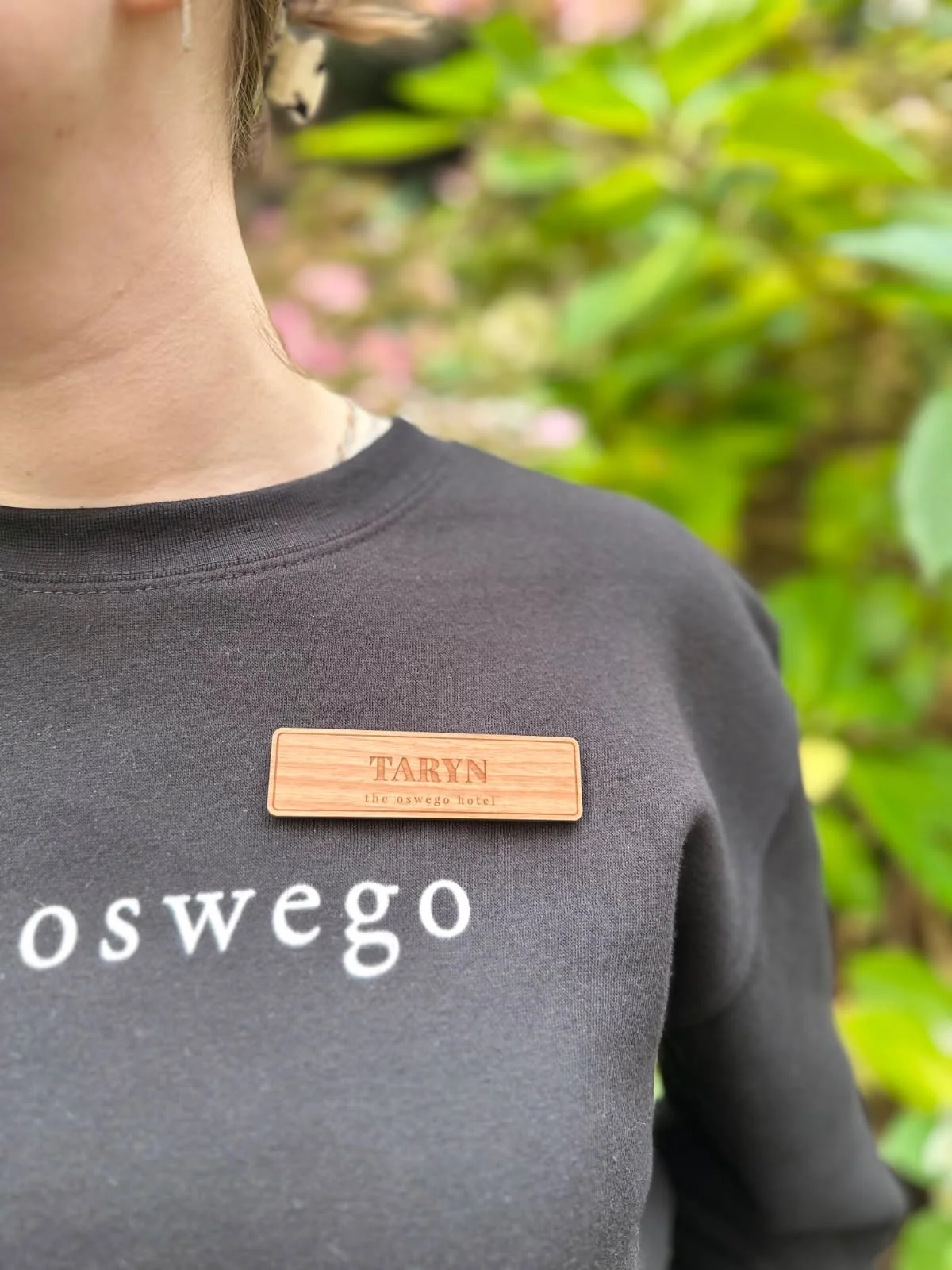 Staff member wearing Oswego Hotel name tag made by Victoria Custom Laser