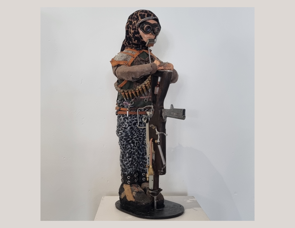 Artist: Paul Kateley. Title: Child of the Apocalypse. Media: Recycled items fused with wood, metal and leather to present a work which is visually engaging and thought provoking. Closer inspection will reveal many known items, repurposed to become an