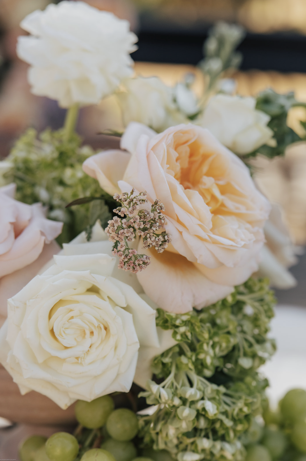 Close-up of a bouquet of white and light peach roses, small pink and white filler flowers, and green berries.