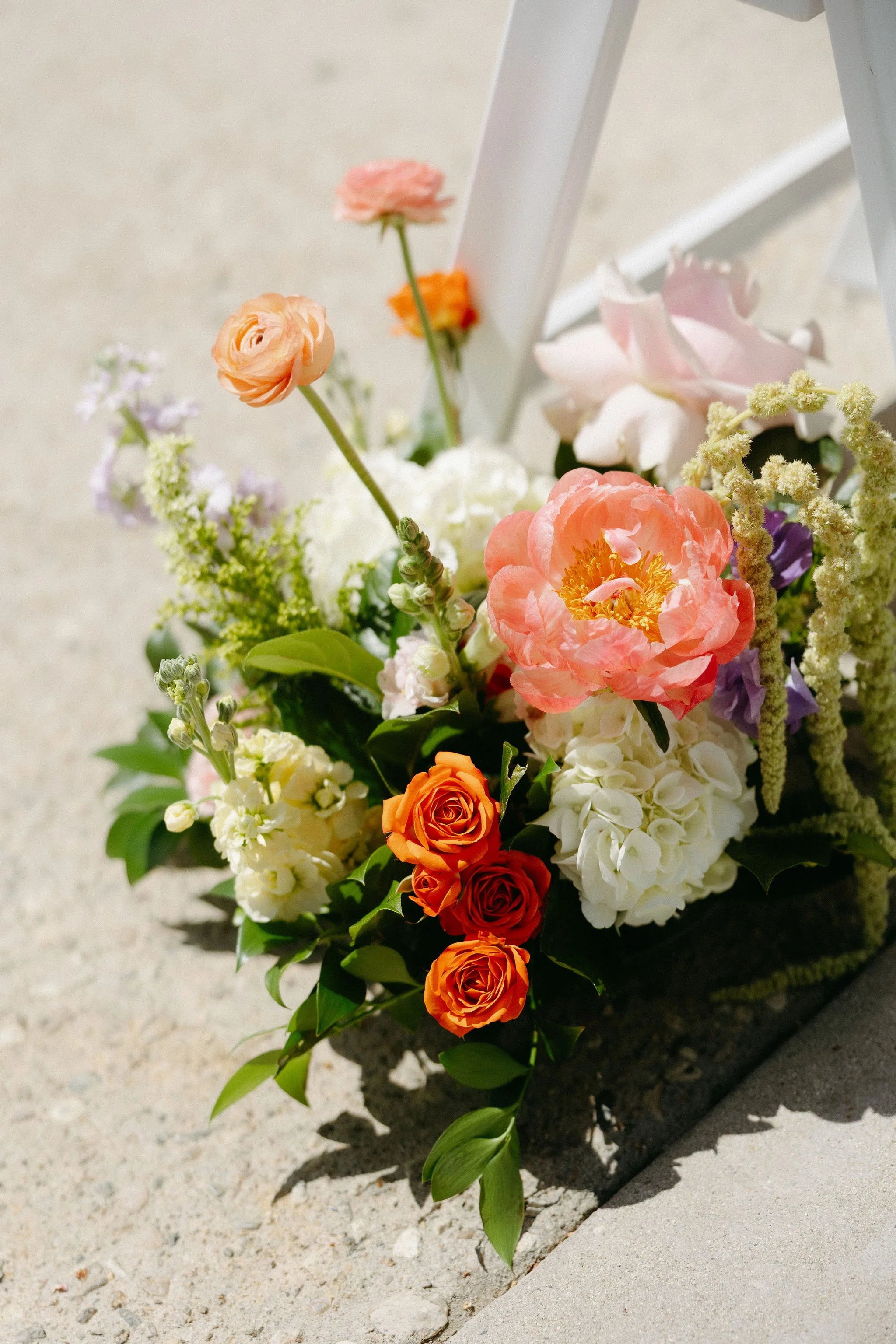 A floral arrangement with various colorful flowers on a concrete surface.