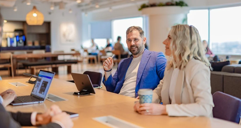 People sitting around a table with laptops talking casually