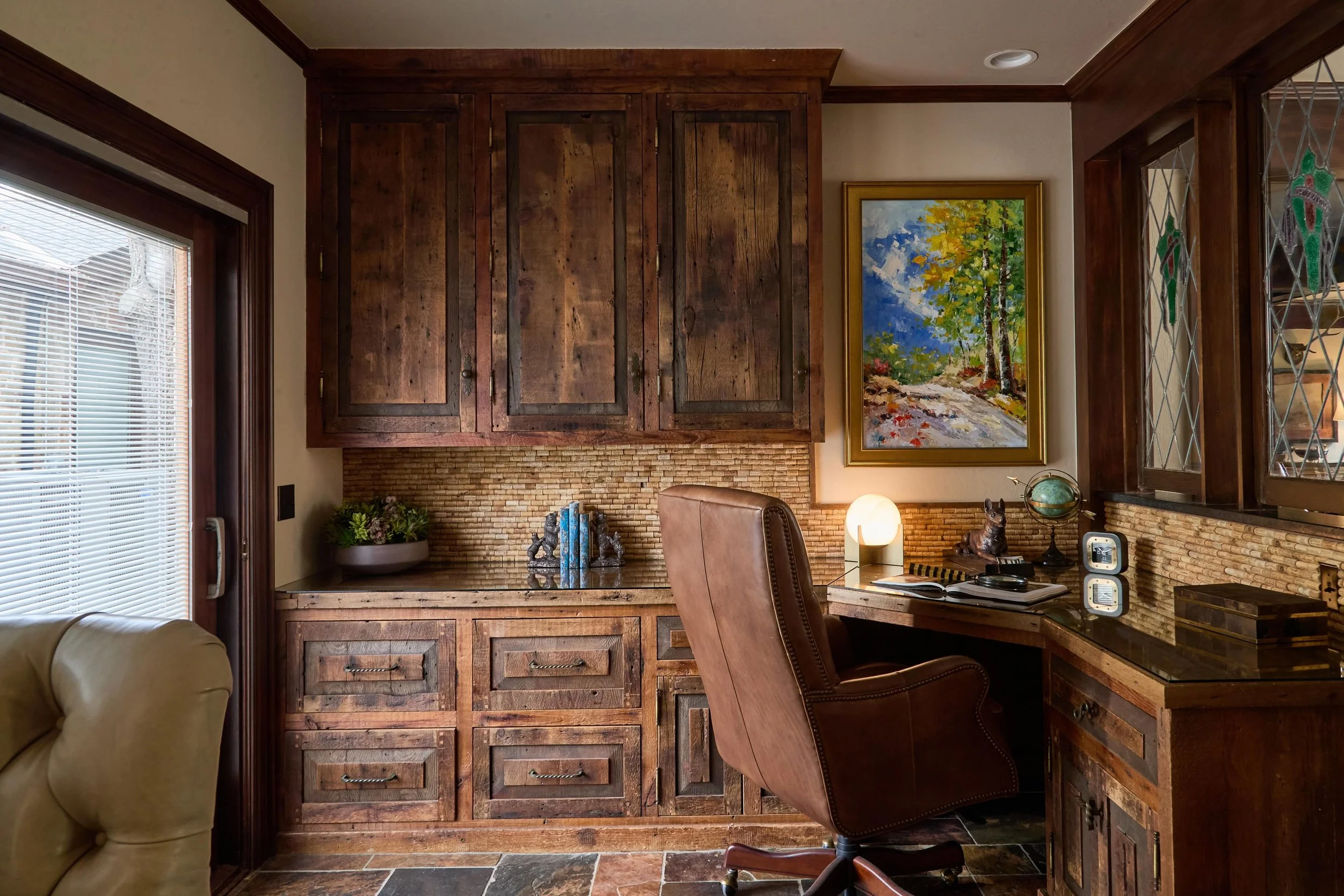 An extension of the family retreat is the inspiring home office. Separated by a pair of stained-glass window panels, this office is a cozy haven. Complete a focused task at the built-in desk from your stylish executive chair or take a more laid-back 