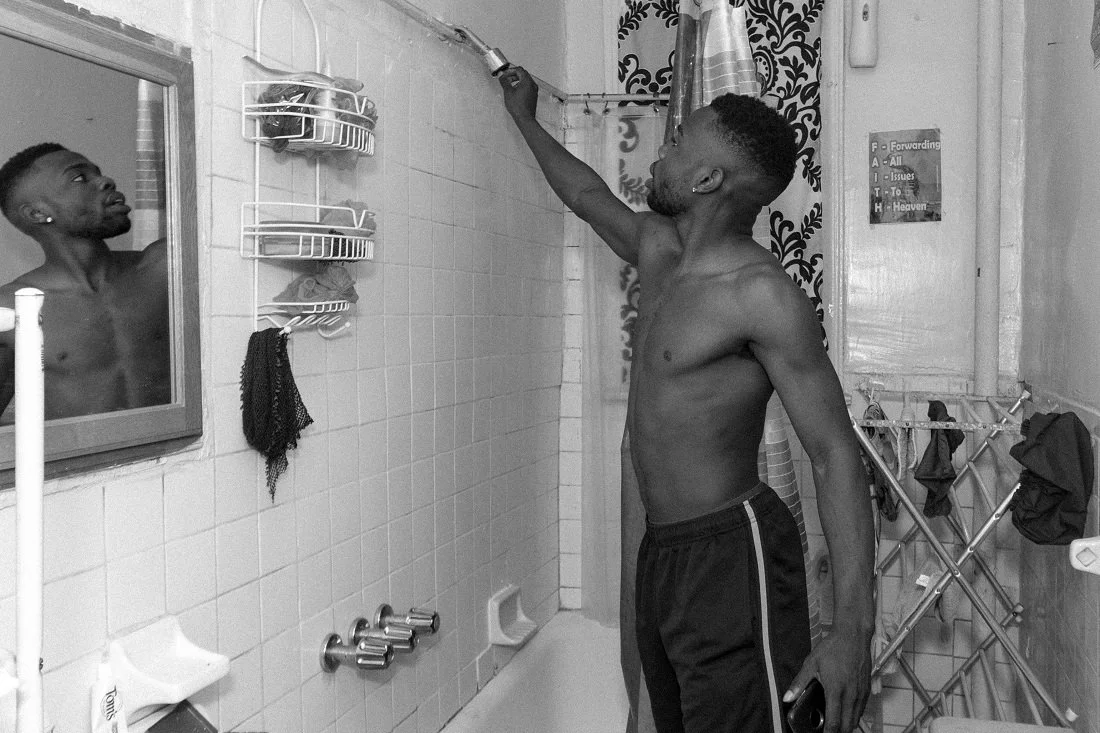 Adjusting his shower head in preparation for a shower. 