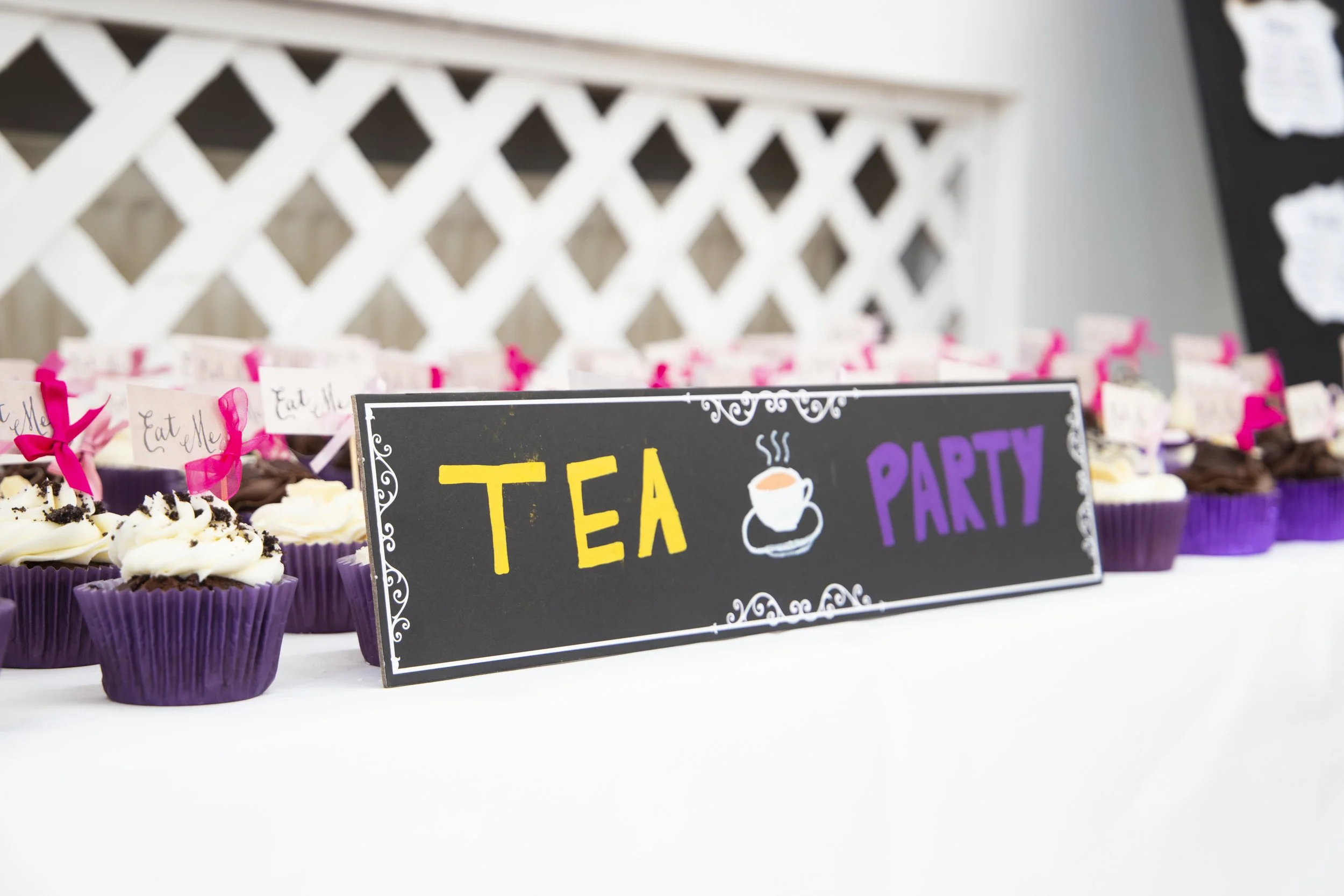 Table with cupcakes and a sign that reads 'Tea Party' with a tea cup illustration.