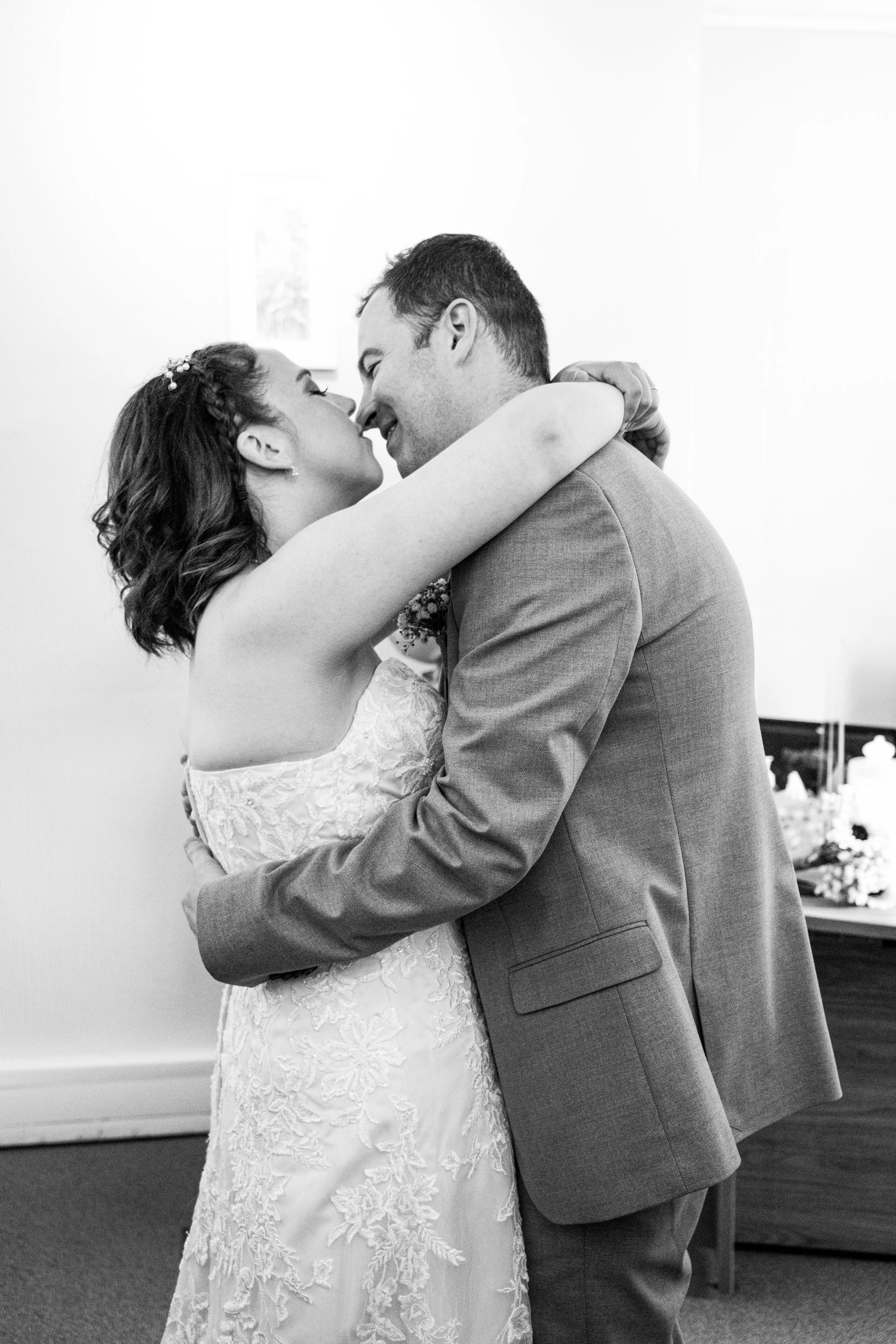 A bride and groom are embracing and about to kiss during a wedding ceremony.