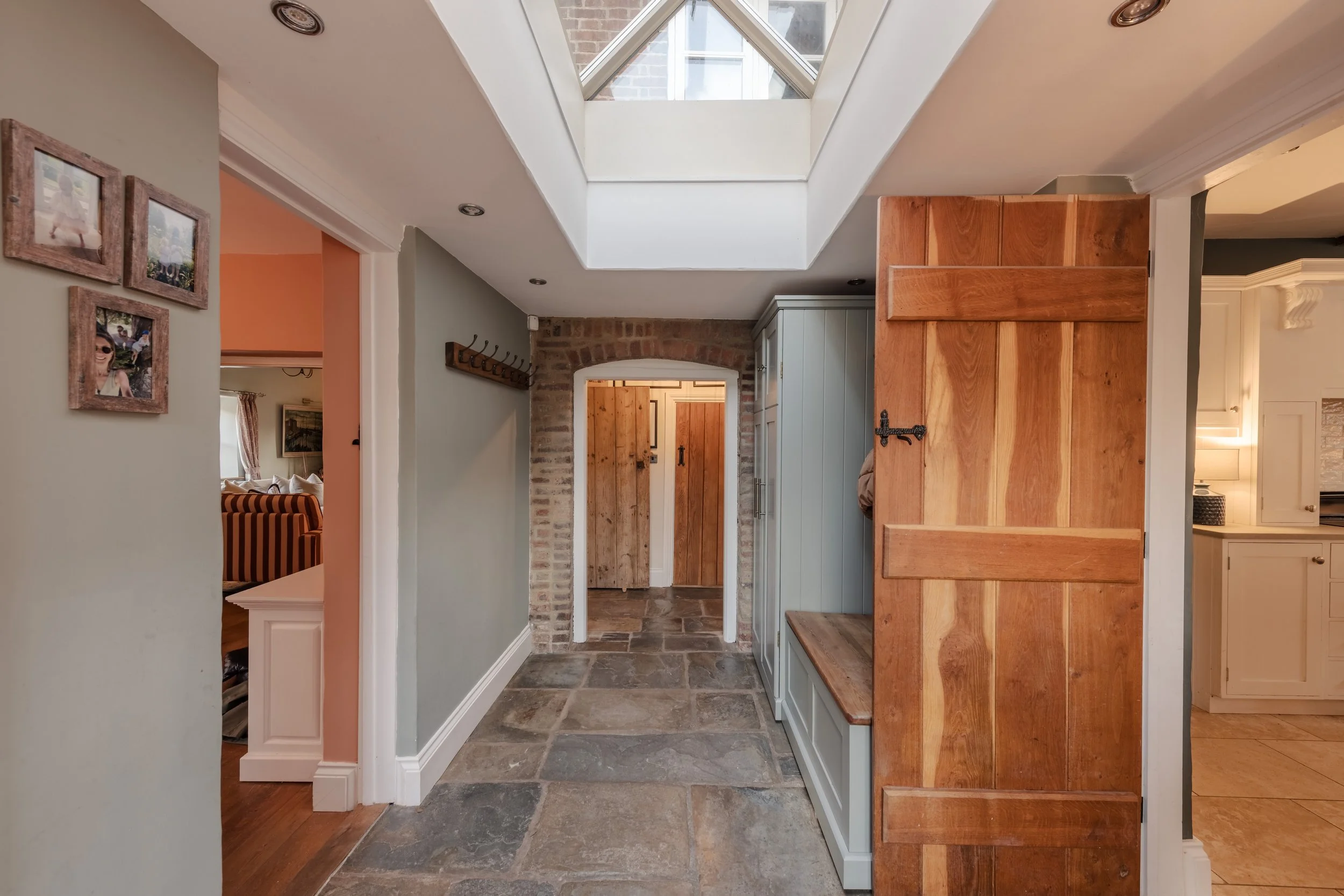 Indoor hallway with stone floor, wooden and pale-colored cabinets, and a skylight on the ceiling.
